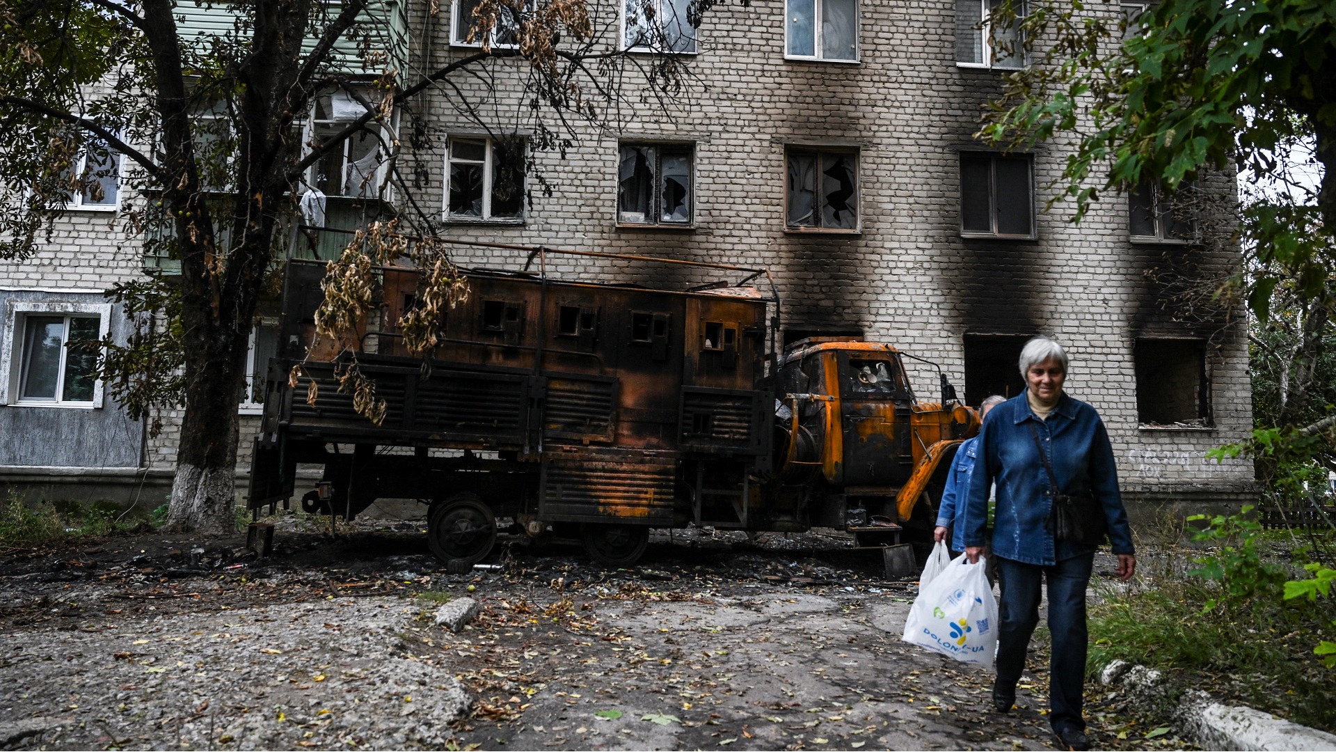 Due donne passano davanti a una casa distrutta a Balaklia, nella regione di Kharkiv, il 17 settembre 2022, durante l'invasione russa dell'Ucraina.  (Foto di Juan Barreto/AFP)