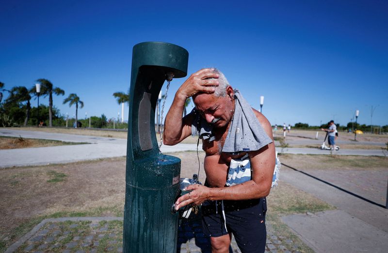 Un hombre se refresca mientras disfruta el día en la costa del Río de la Plata durante una ola de calor 