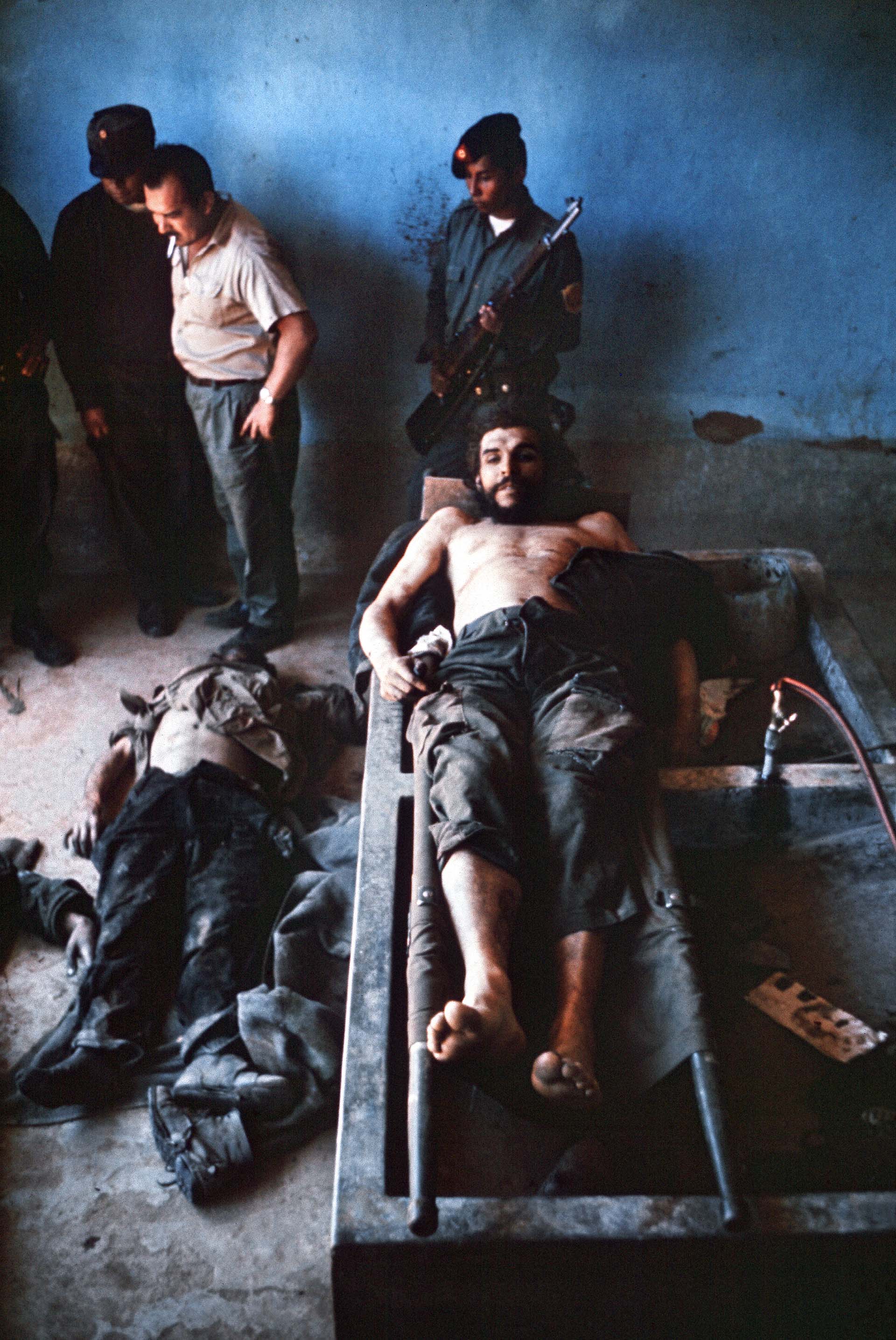 La imagen del Che Guevara en el hospital de Vallegrande desde otro ángulo. En el piso, uno de sus combatientes muertos en La Higuera / AFP PHOTO / MARC HUTTEN