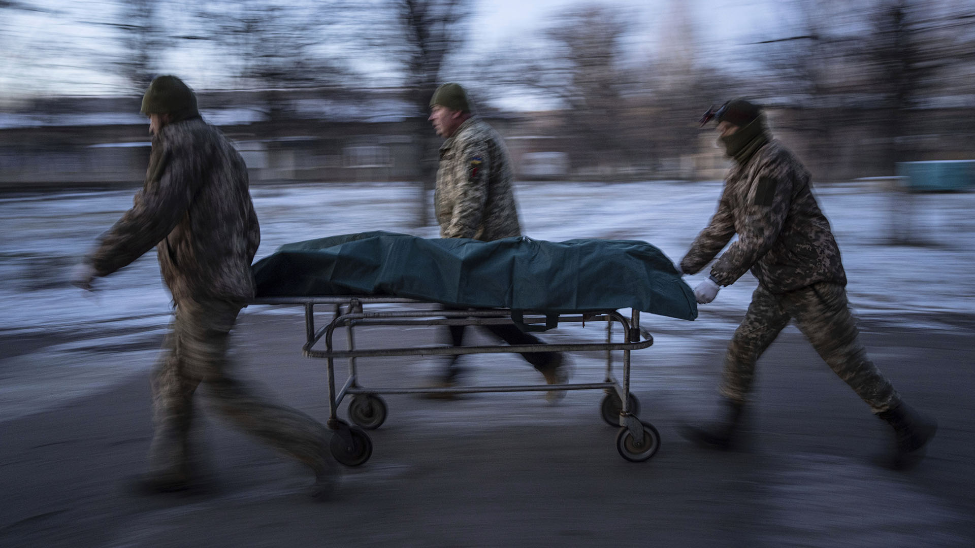 Ukrainian military medics carry a stretcher with the body of their slain comrade to a morgue in the Donetsk region, Ukraine, Monday, Jan. 9, 2023. (AP Photo/Evgeniy Maloletka)