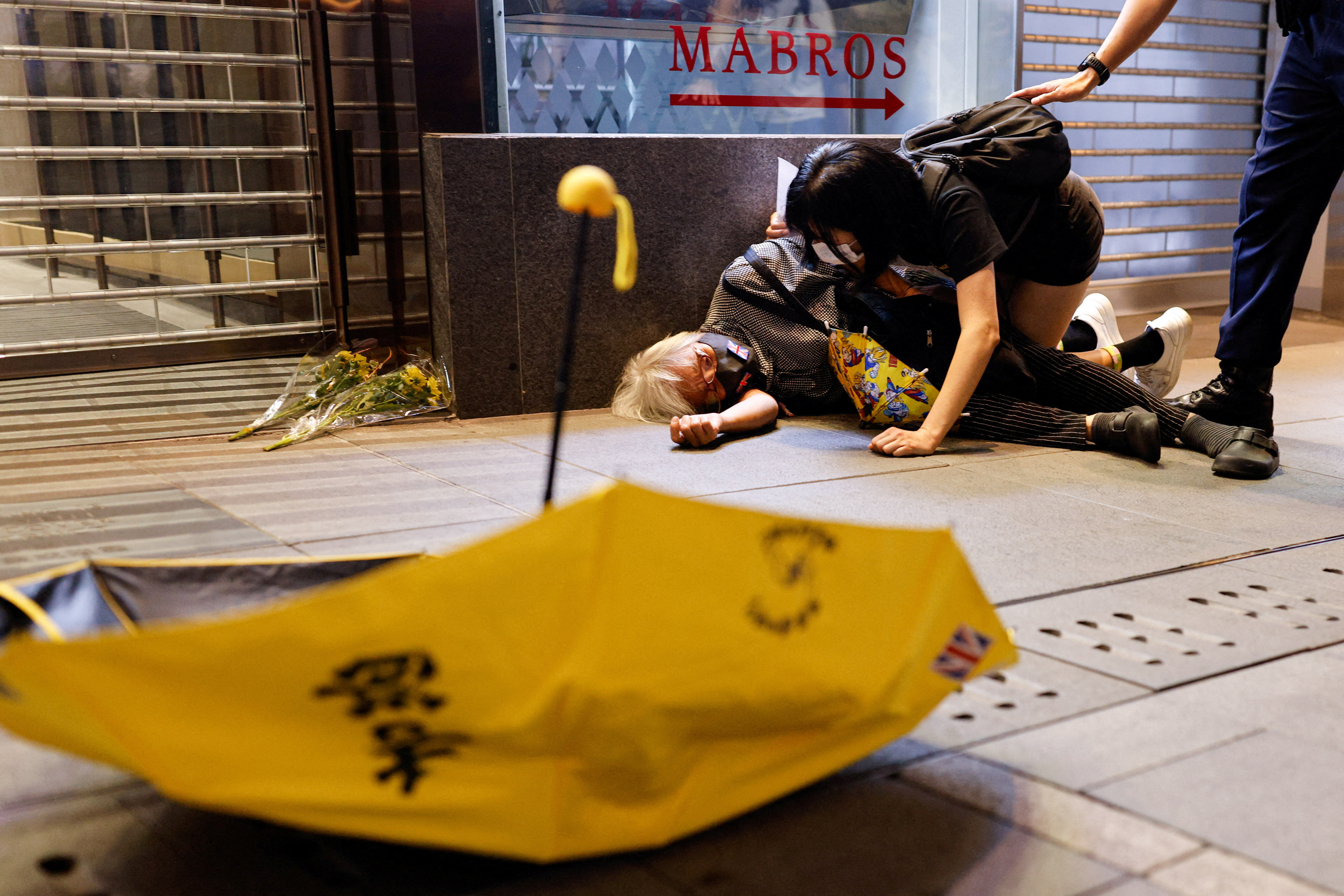 Un manifestante yace en el suelo tras ser reprimido durante una protesta por las restricciones a la enfermedad del coronavirus (COVID-19) en China, durante una conmemoración de las víctimas de un incendio en Urumqi (Reuters)
