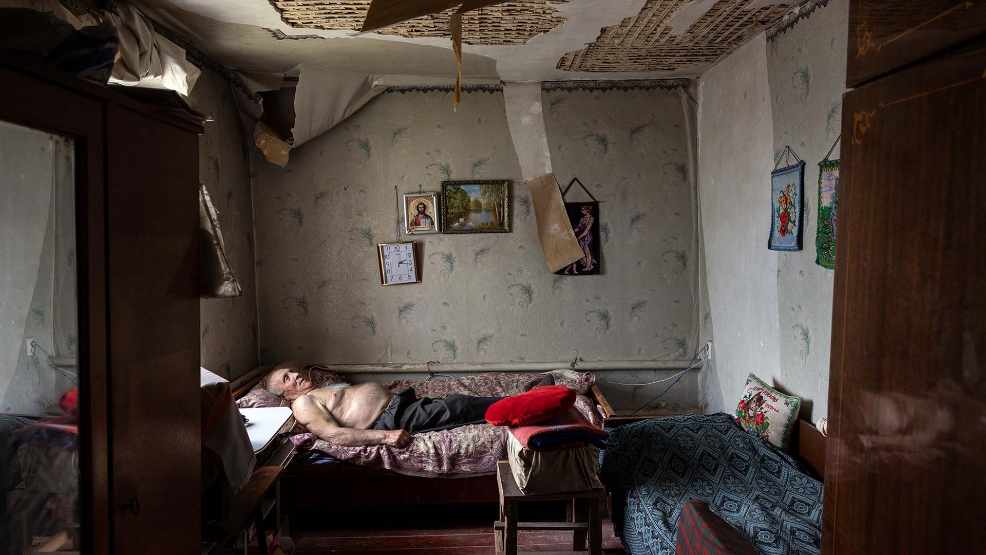 Olexiy Pshenychnykh, de 85 años, descansa en su casa dañada por la guerra en Vilkhivka, al este de Kharkiv el 18 de mayo de 2022, tras la retirada de las fuerzas de ocupación rusas (Fotos de John Moore/Getty Images)