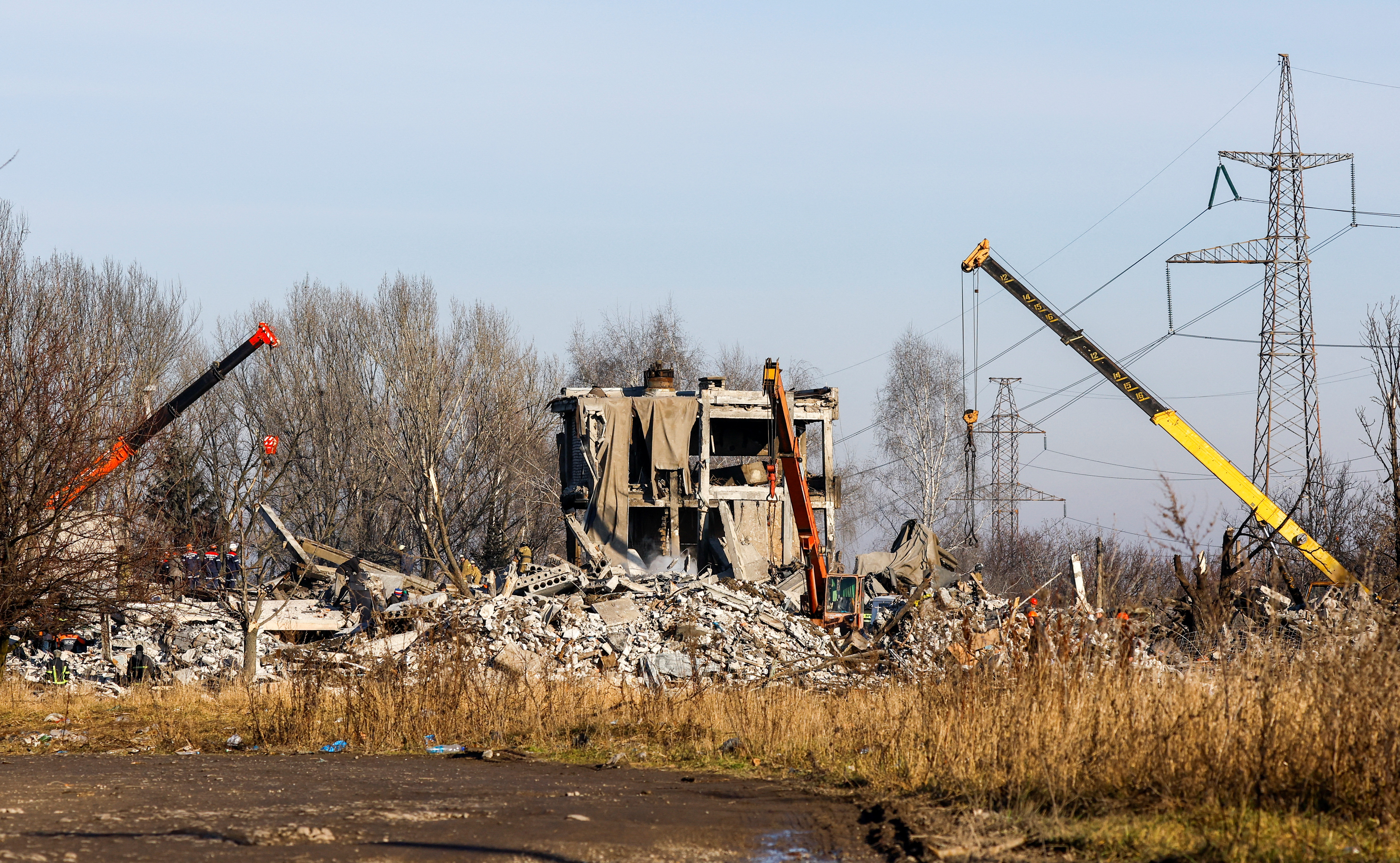 Remoción de escombros en el centro educativo de Makiikva, usado como base y depósito por las tropas rusas (Reuters)
