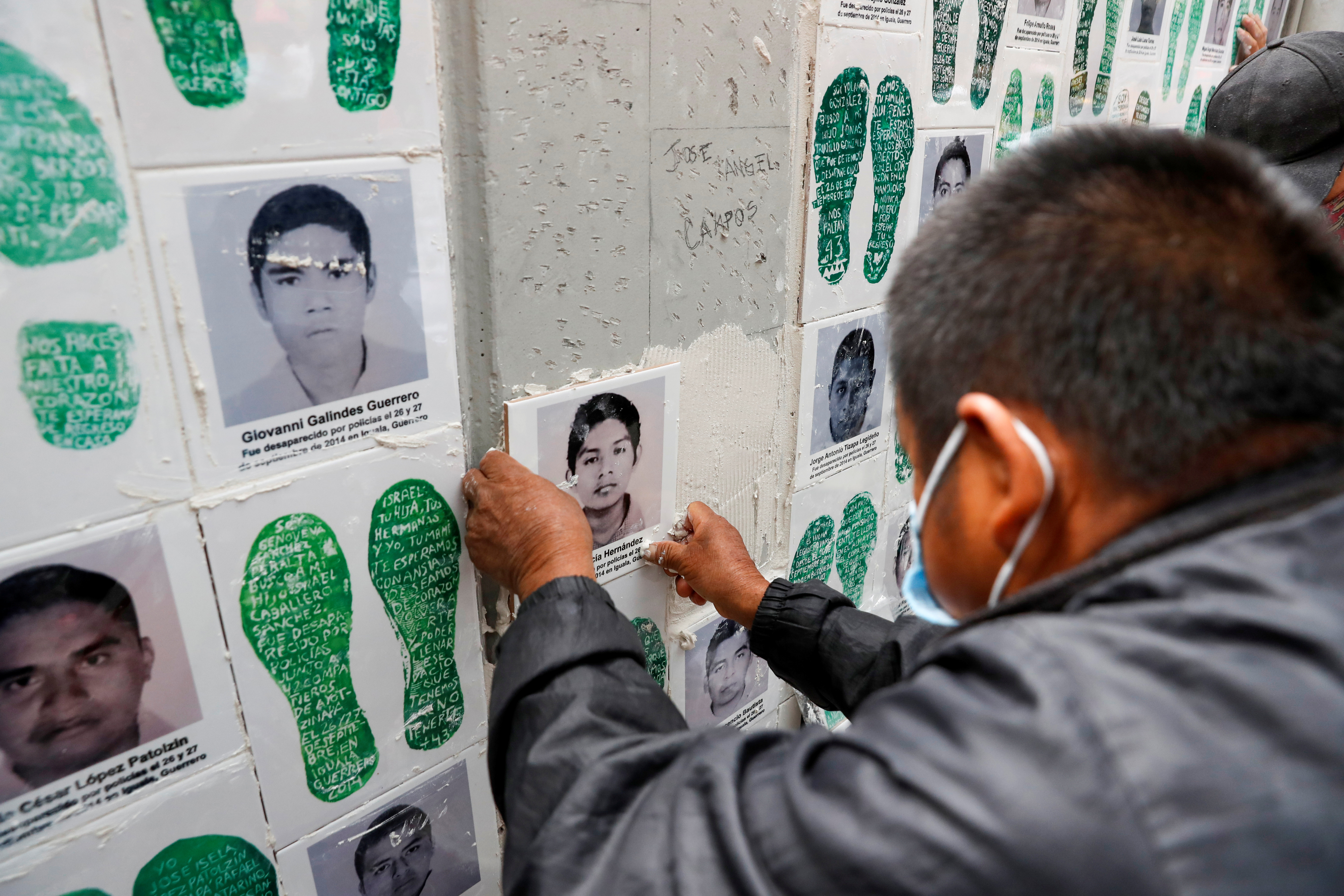 Un familiar de un estudiante desaparecido coloca una cerámica con su imagen en una pared durante una protesta frente a la Fiscalía General, antes del sexto aniversario de la desaparición de 43 estudiantes de la Escuela Normal Rural de Ayotzinapa, en la Ciudad de México, México el 25 de septiembre de 2020.