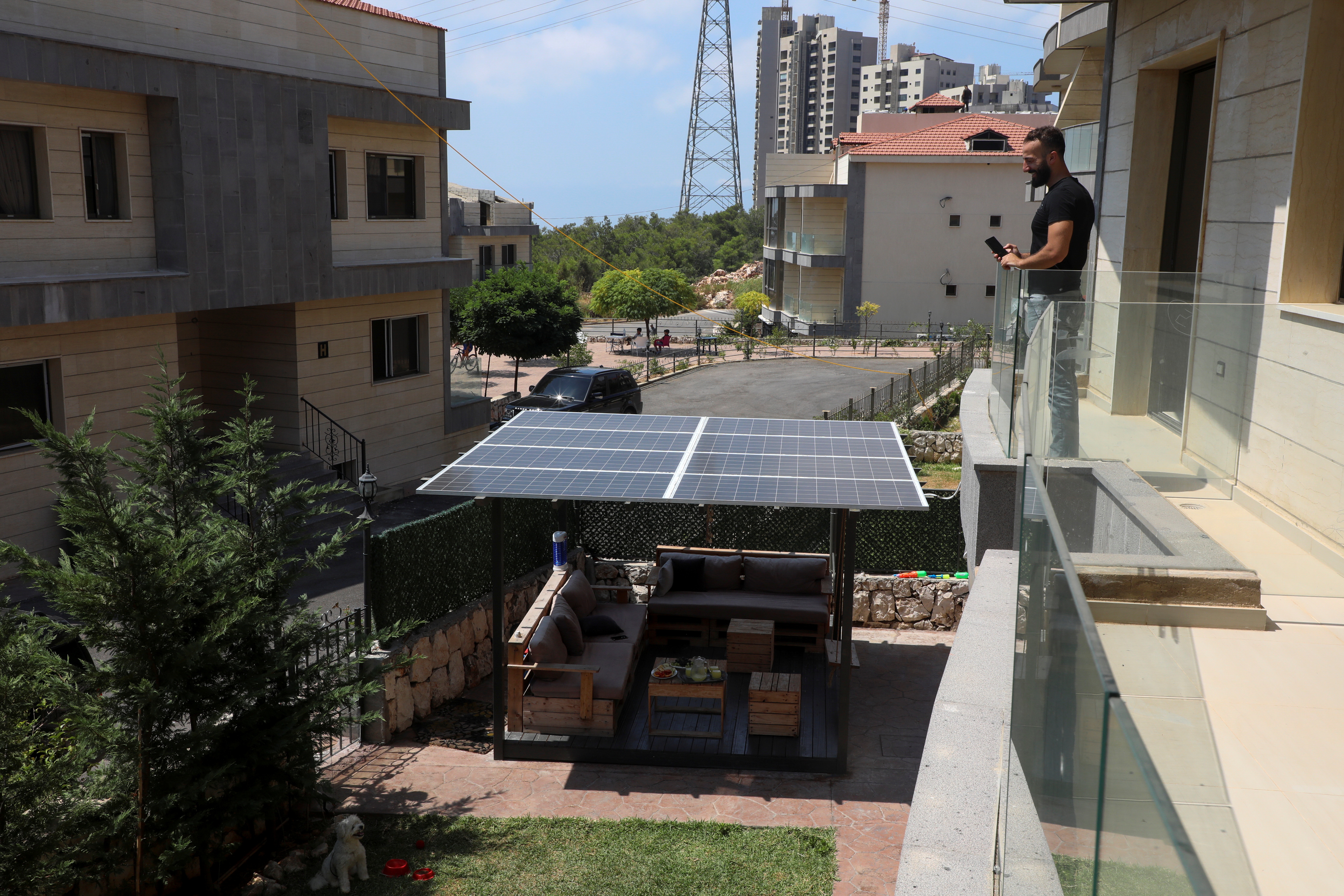 Un libanés se asoma a un balcón mientras observa un panel solar que instaló en su casa de Khaldeh. (REUTERS/Mohamed Azakir)