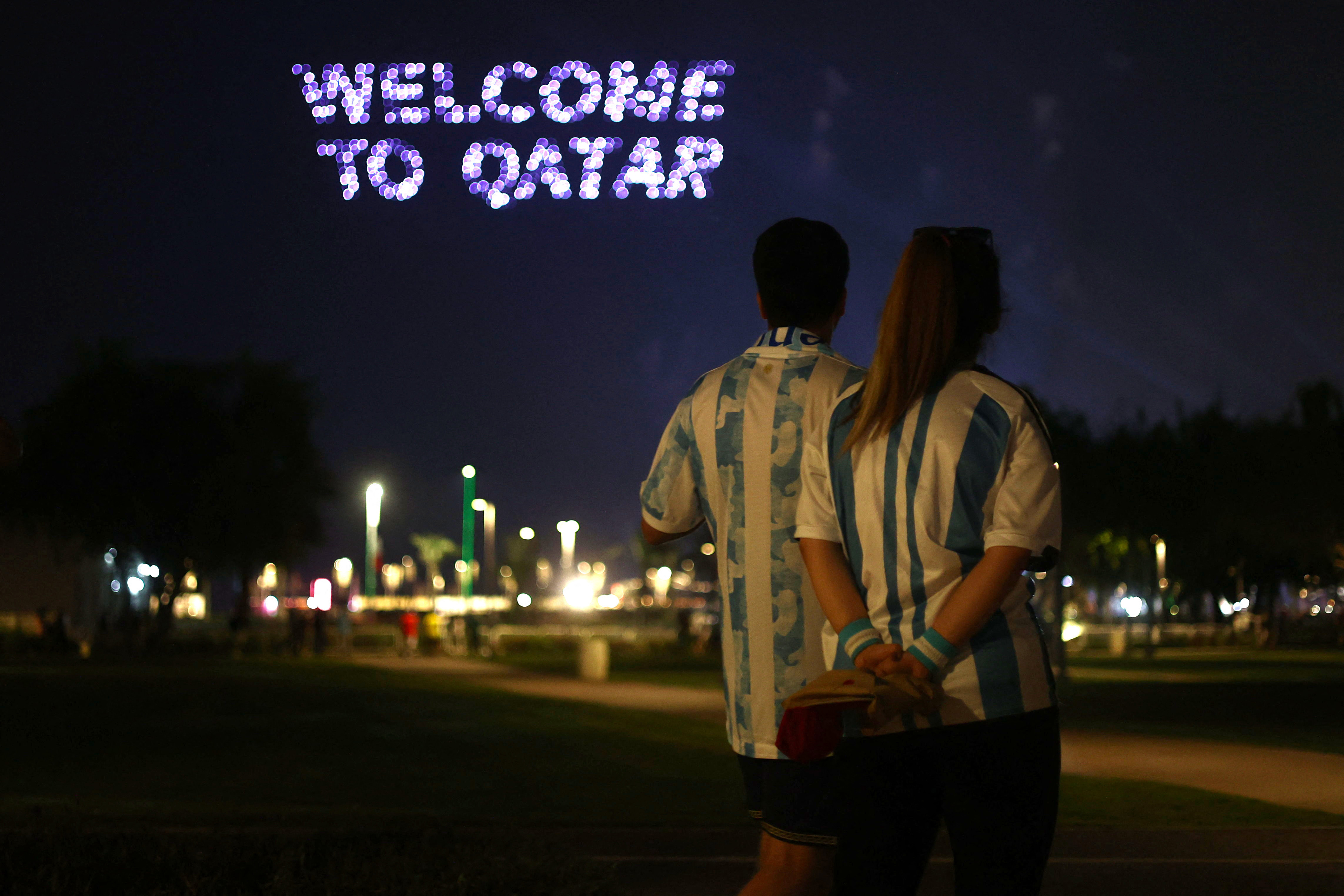 Soccer Football - FIFA World Cup Qatar 2022 - Doha, Qatar - November 22, 2022 Argentina fans look at a 'Welcome to Qatar' sign in the Corniche fan zone during a light and fireworks show REUTERS/Pedro Nunes