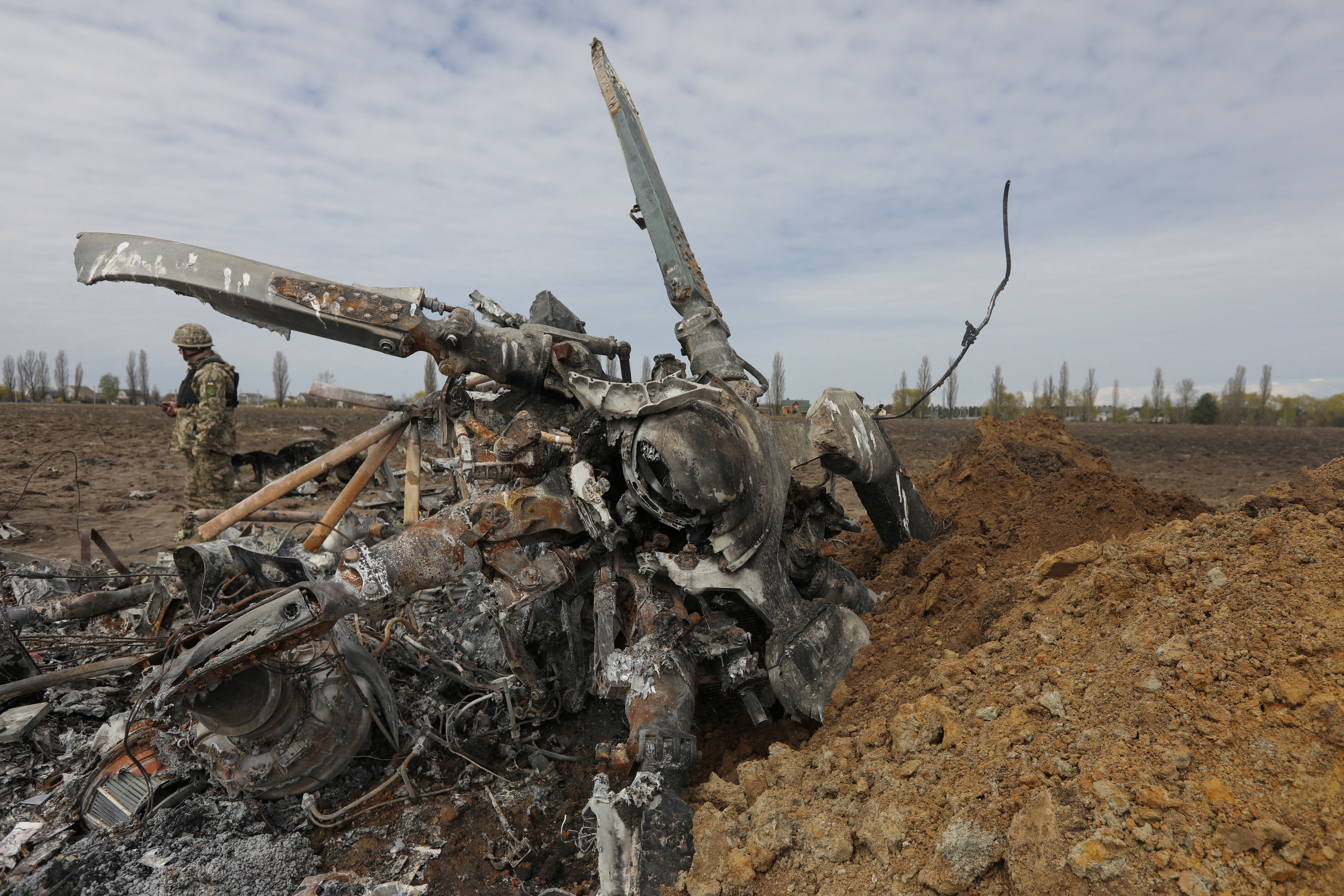 Un militar ucraniano camina cerca de los restos de un helicóptero ruso Mi-8 que se estrelló durante la invasión de Rusia cerca del pueblo de Havronshchyna en la región de Kiev (REUTERS/Mykola Tymchenko/Archivo)