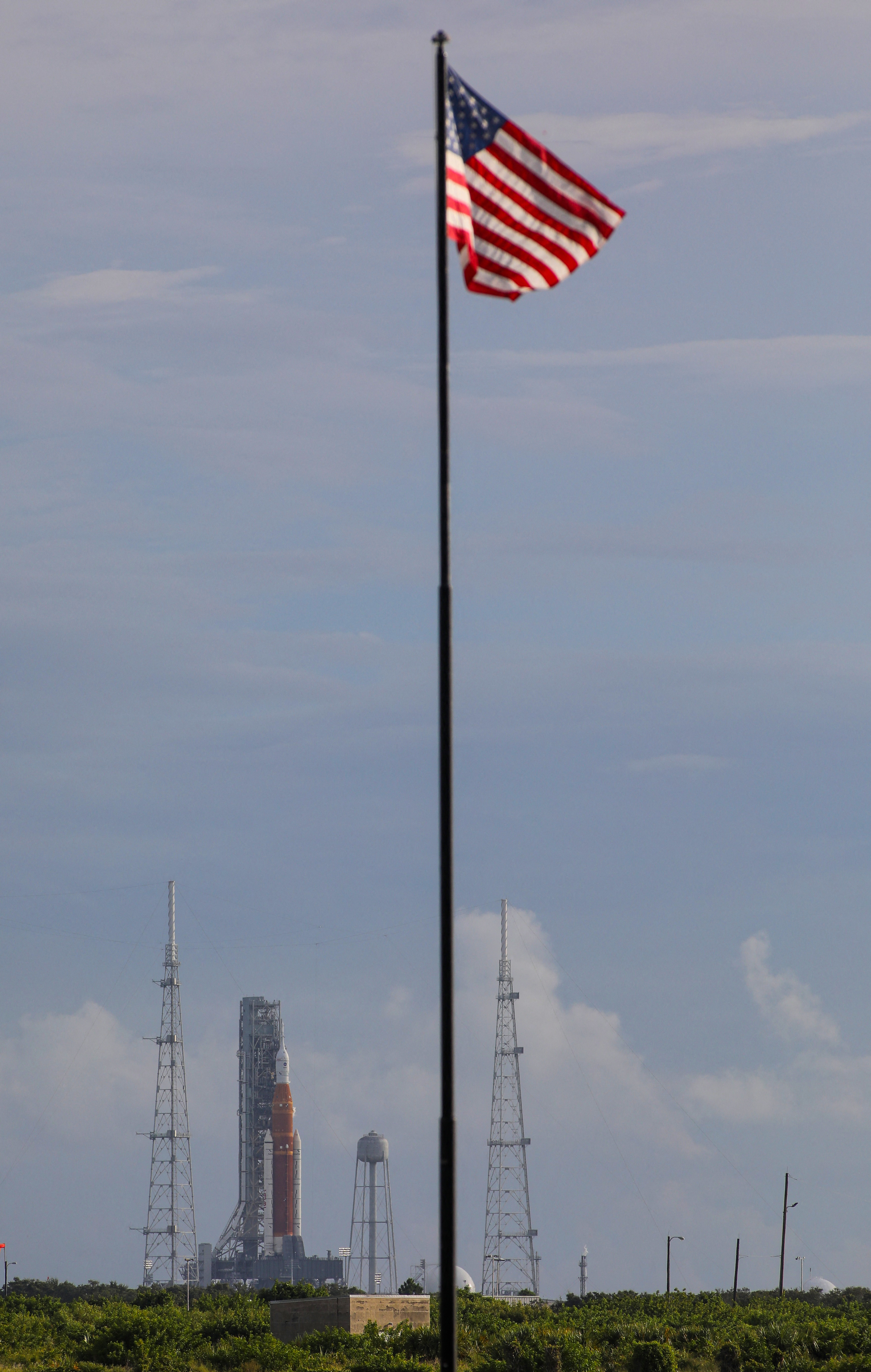 A U.S. flag flutters as  NASA's next-generation moon rocket, the Space Launch System (SLS) , with its Orion crew capsule on top, sits on the pad before the launch of the Artemis I mission was scrubbed, at Cape Canaveral, Florida, U.S., August 29, 2022. REUTERS/Thom Baur