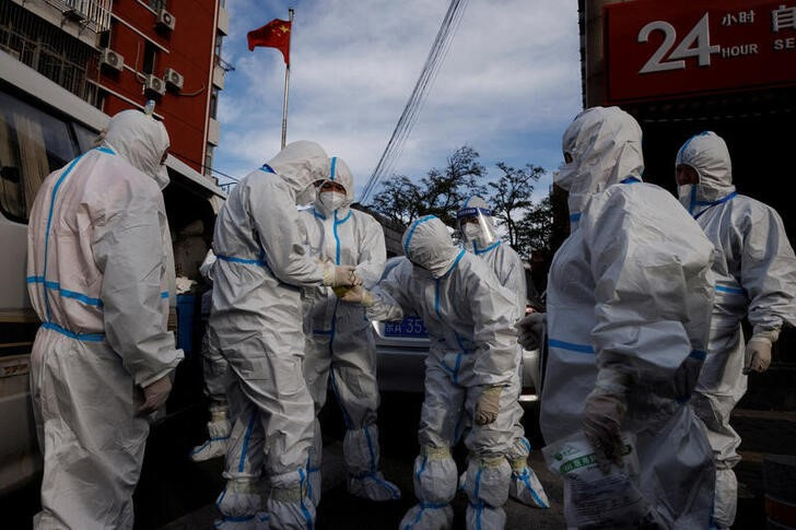 Trabajadores de prevención pandémica vestidos con trajes protectores preparándose para entrar en un complejo de departamentos en confinamiento por un brote de COVID-19 en Pekín. REUTERS/Thomas Peter