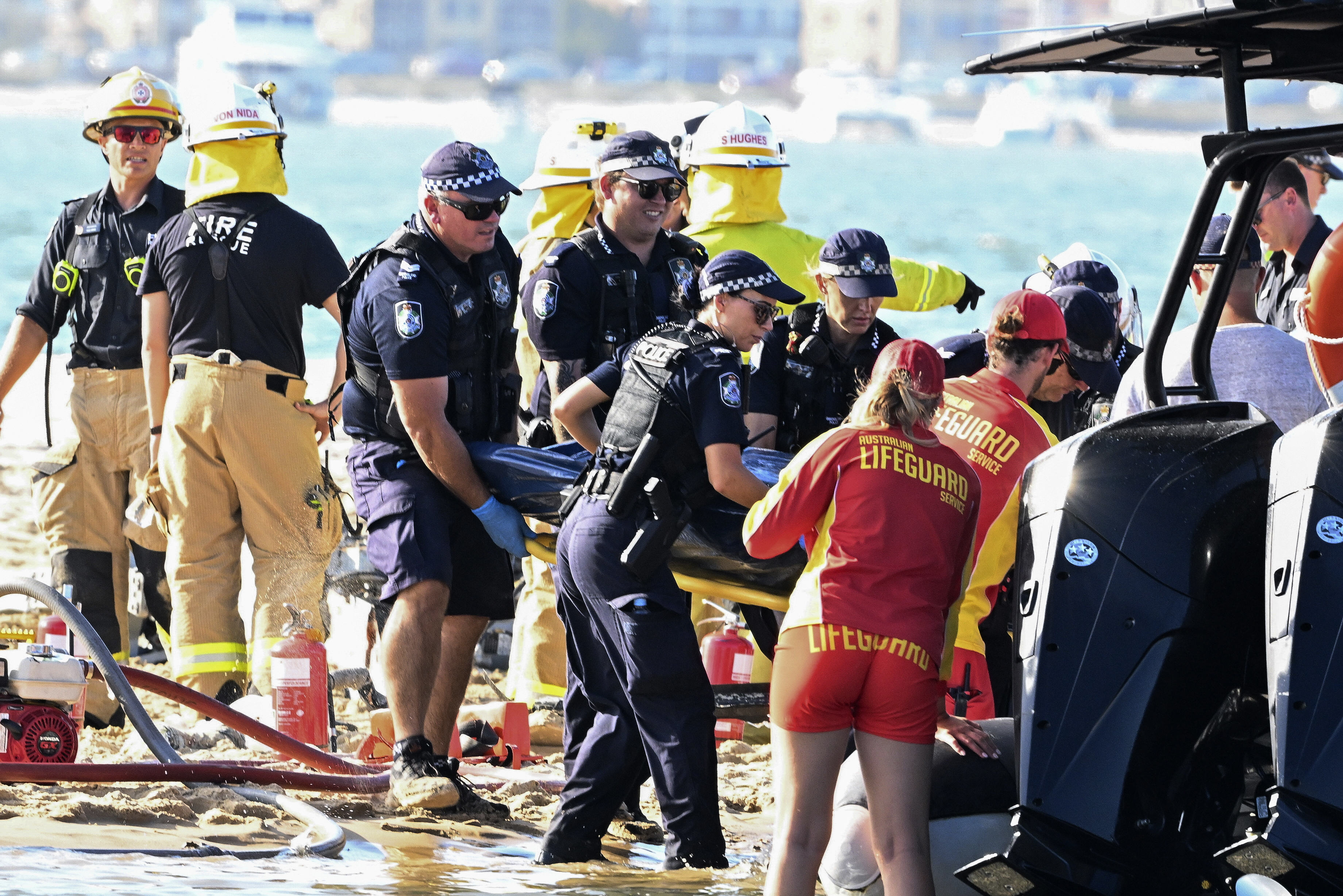 Los trabajadores de emergencia retiran un cuerpo de la escena de la colisión de un helicóptero cerca de Seaworld, en Gold Coast, Australia, el lunes 2 de enero de 2023.  (Imagen de Dave Hunt/AAP vía AP)

