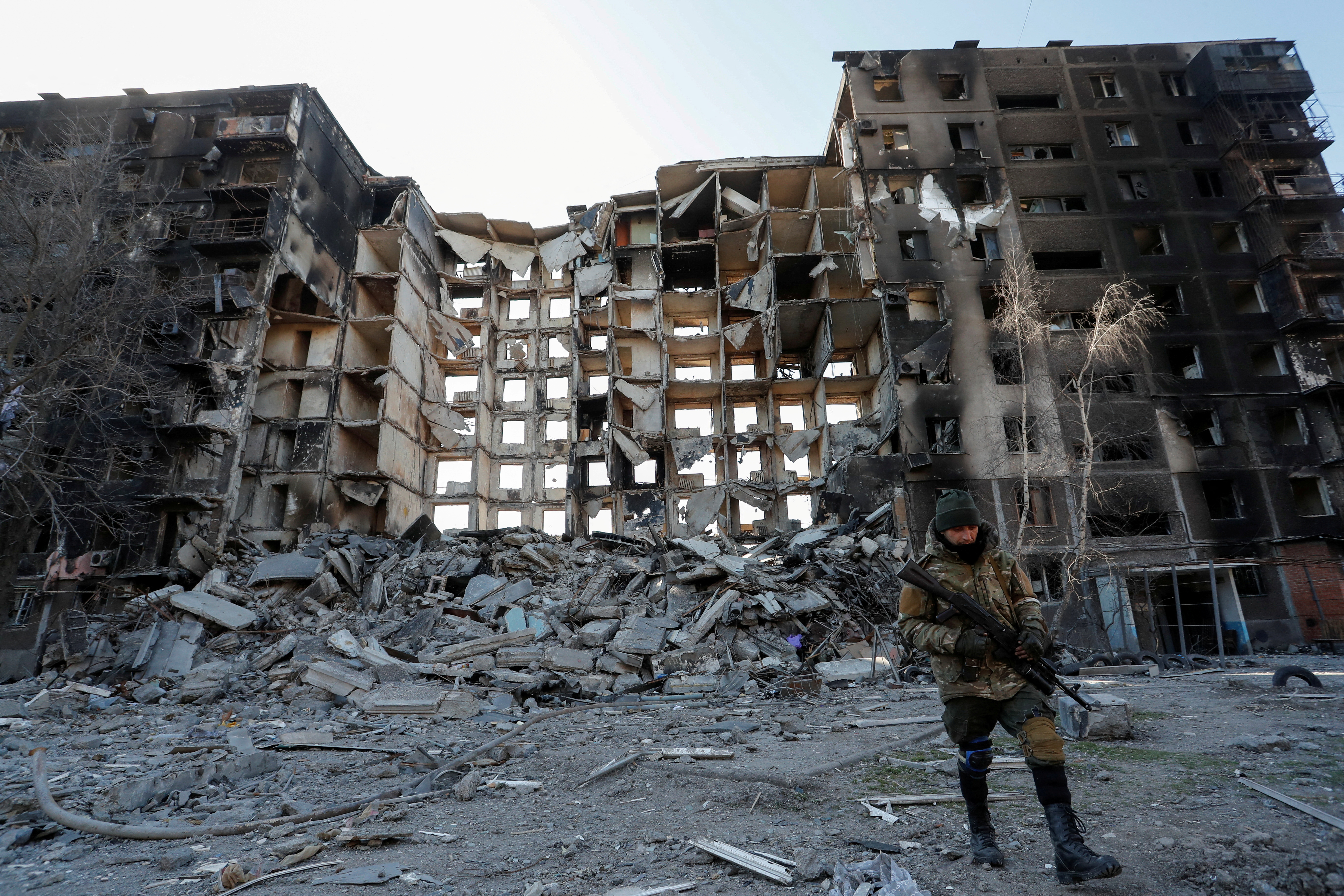 Un miembro de las tropas prorrusas camina cerca de un edificio de apartamentos destruido por el conflicto ucraniano-ruso en la sitiada ciudad portuaria del sur de Mariupol, Ucrania, 28 de marzo de 2022. REUTERS/Alexander Ermochenko IMÁGENES TPX DEL DÍA