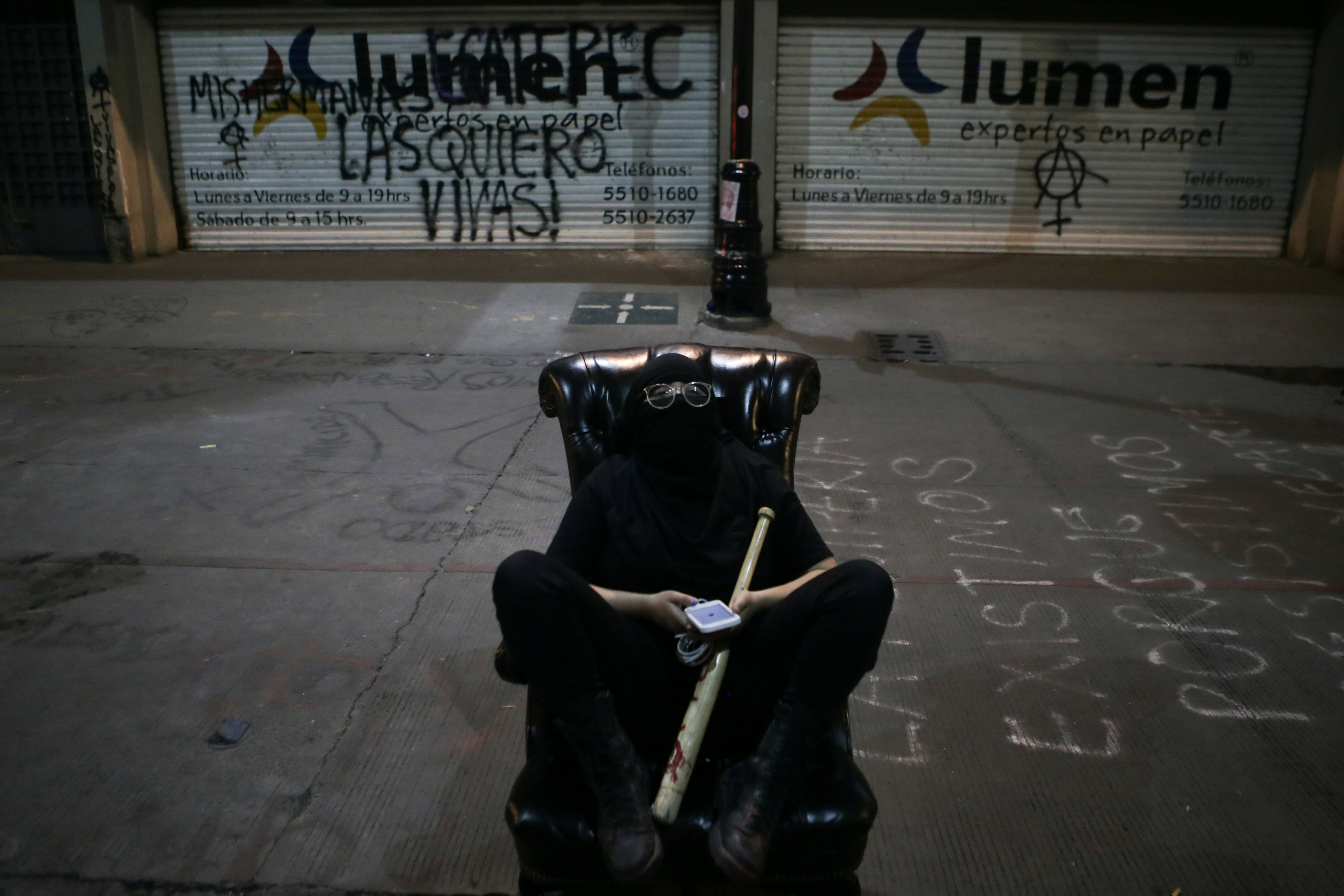 Una integrante de un colectivo feminista sentada en la silla de una Comisión Nacional de Derechos Humanos mientras monta guardia en la calle durante la noche fuera de las instalaciones del edificio de la Comisión Nacional de Derechos Humanos, en apoyo a las víctimas de violencia de género, en la Ciudad de México, México 11 de septiembre , 2020. Foto tomada el 11 de septiembre de 2020.