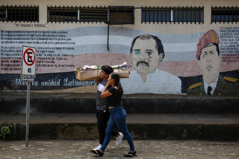 Nicaragüenses pasan frente a un mural que muestra a Ortega y a Hugo Chávez en Managua el 7 de enero de 2022 (REUTERS/Maynor Valenzuela)