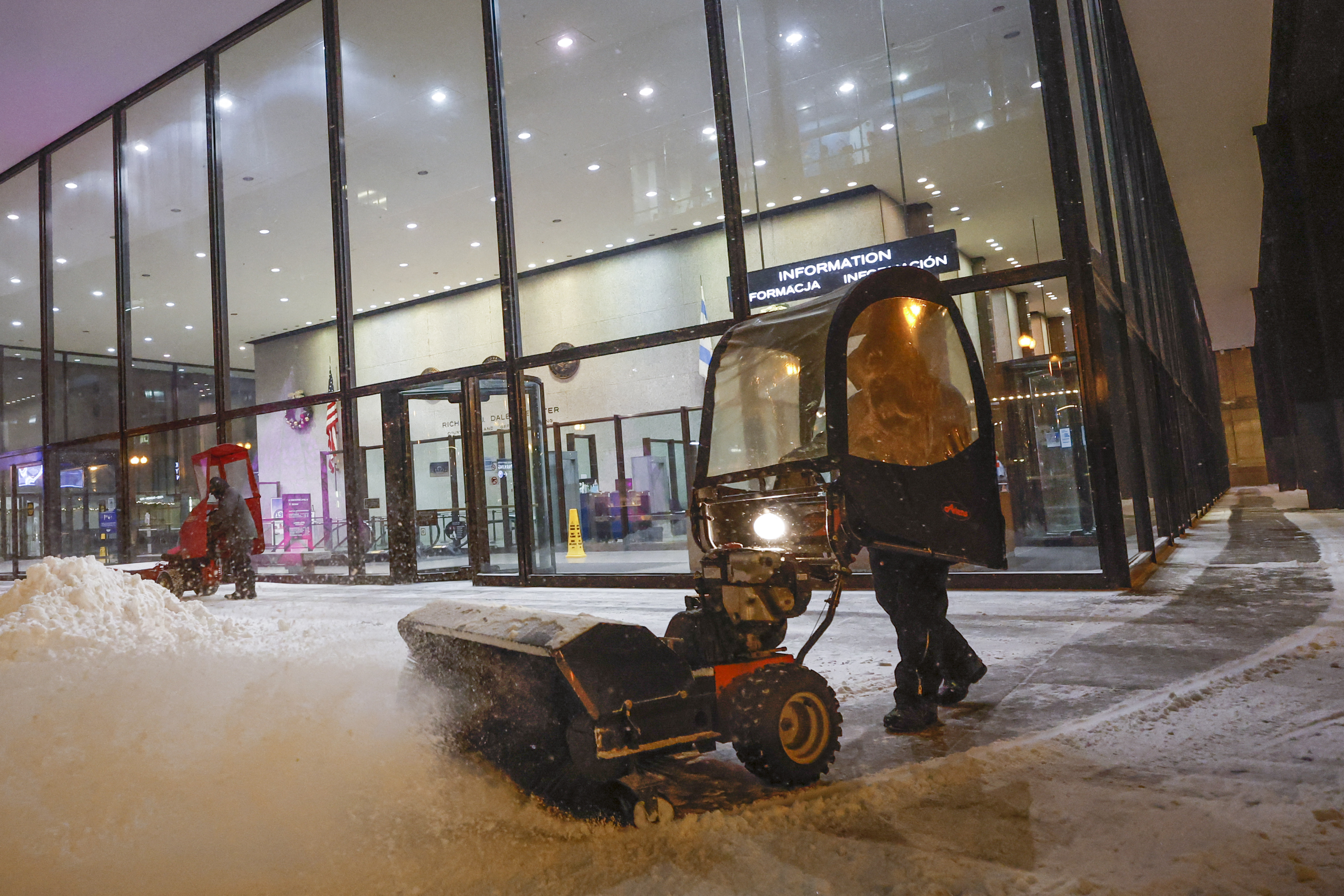 Una persona utiliza un soplador de nieve para limpiar una acera fuera de Union Station en Chicago, Illinois, el 22 de diciembre de 2022, durante una tormenta de invierno antes de las vacaciones de Navidad. (Foto de KAMIL KRZACZYNSKI / AFP)