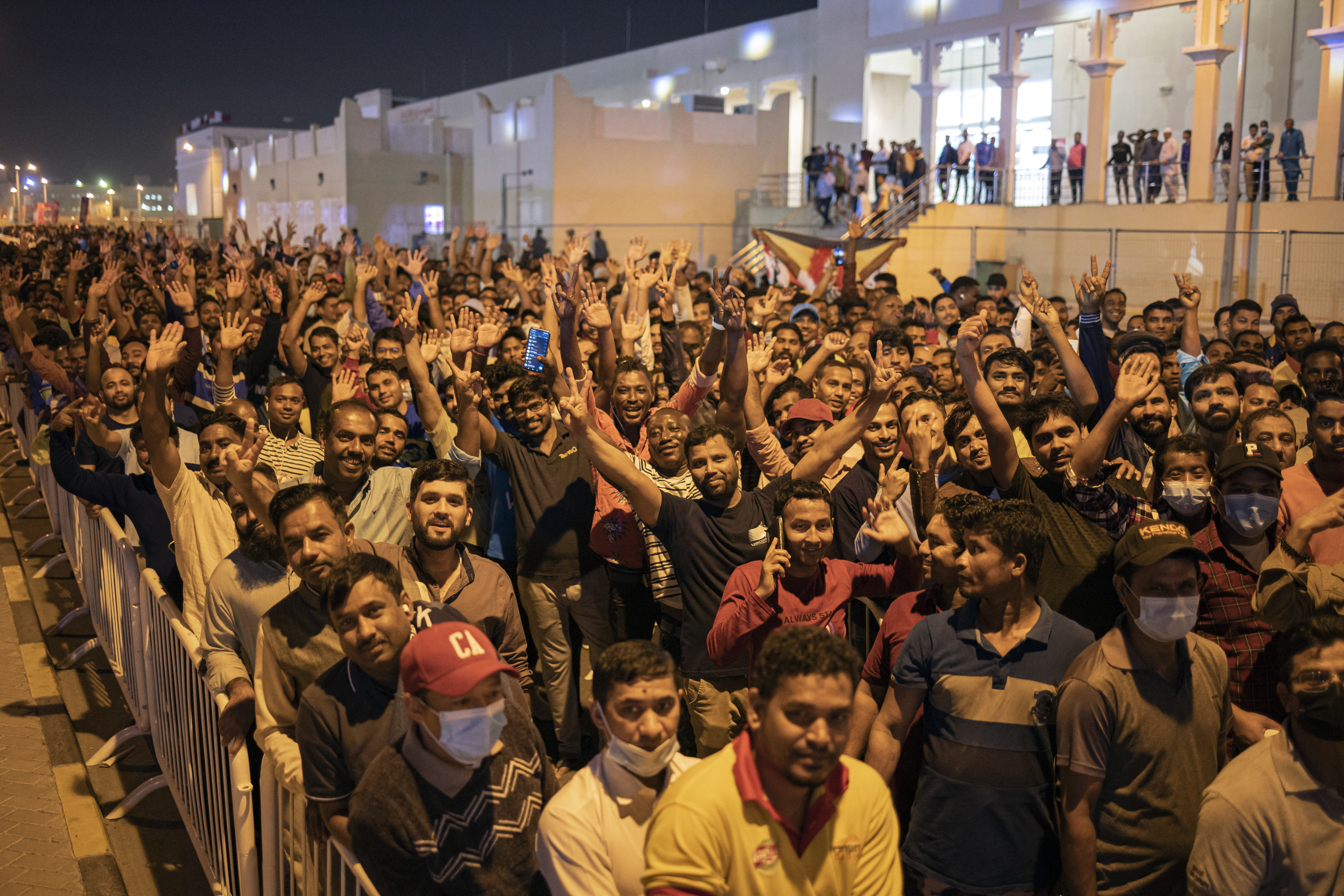 Trabajadores migrantes en Doha observan un partido del Mundial (Reuters)