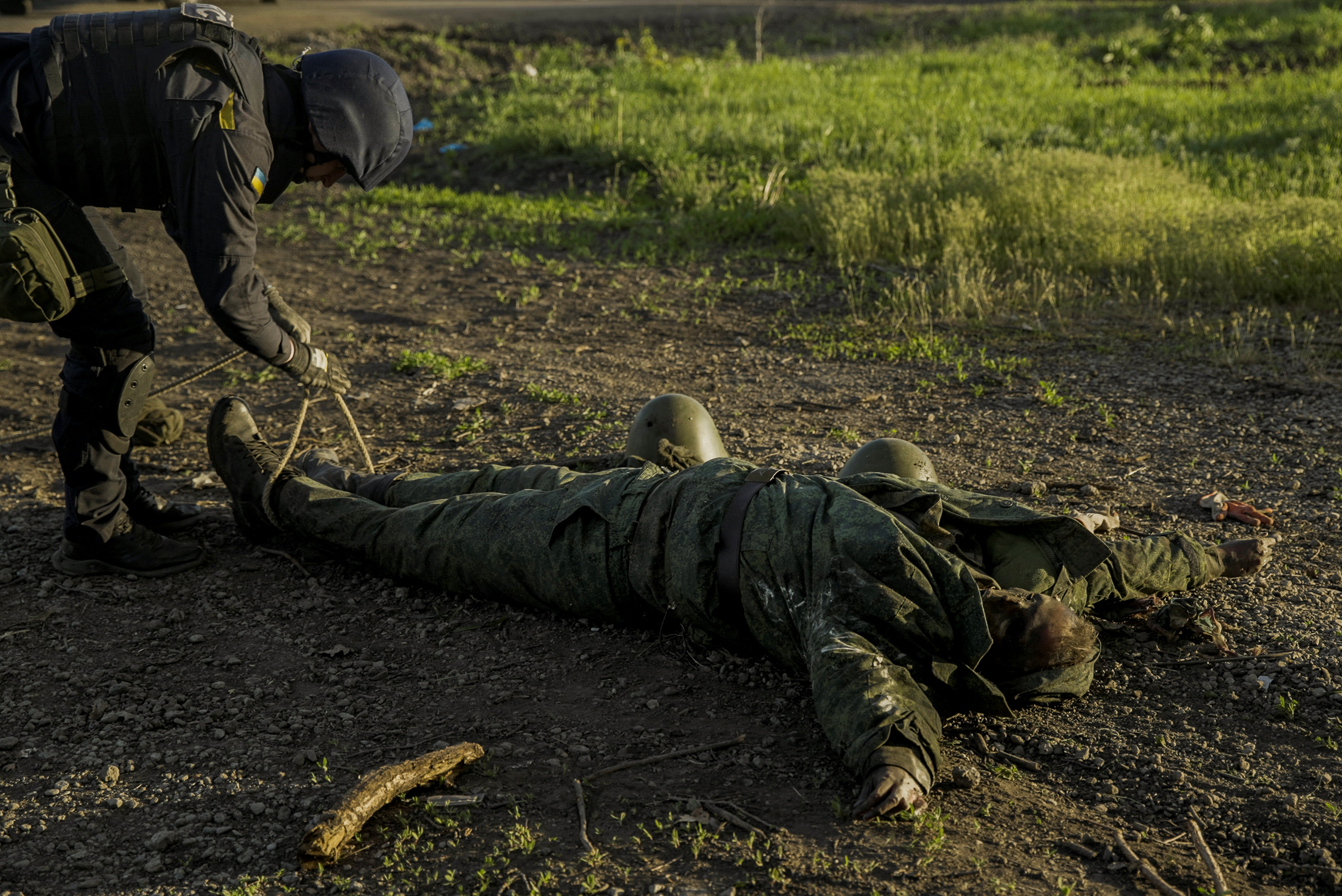Un soldado ucraniano revisa si el militar ruso muerto tiene explosivos en su vestimenta antes de ser retirado del campo de batalla en Kharkiv (Reuters)