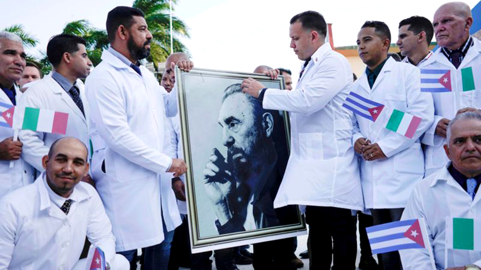 Médicos cubanos sostienen una imagen del fallecido dictador cubano Fidel Castro durante una ceremonia de despedida antes de partir a Italia para ayudar al país europeo, en medio de la pandemia de coronavirus, en La Habana, Cuba. 21 de marzo de 2020 (REUTERS/Alexandre Meneghini)
