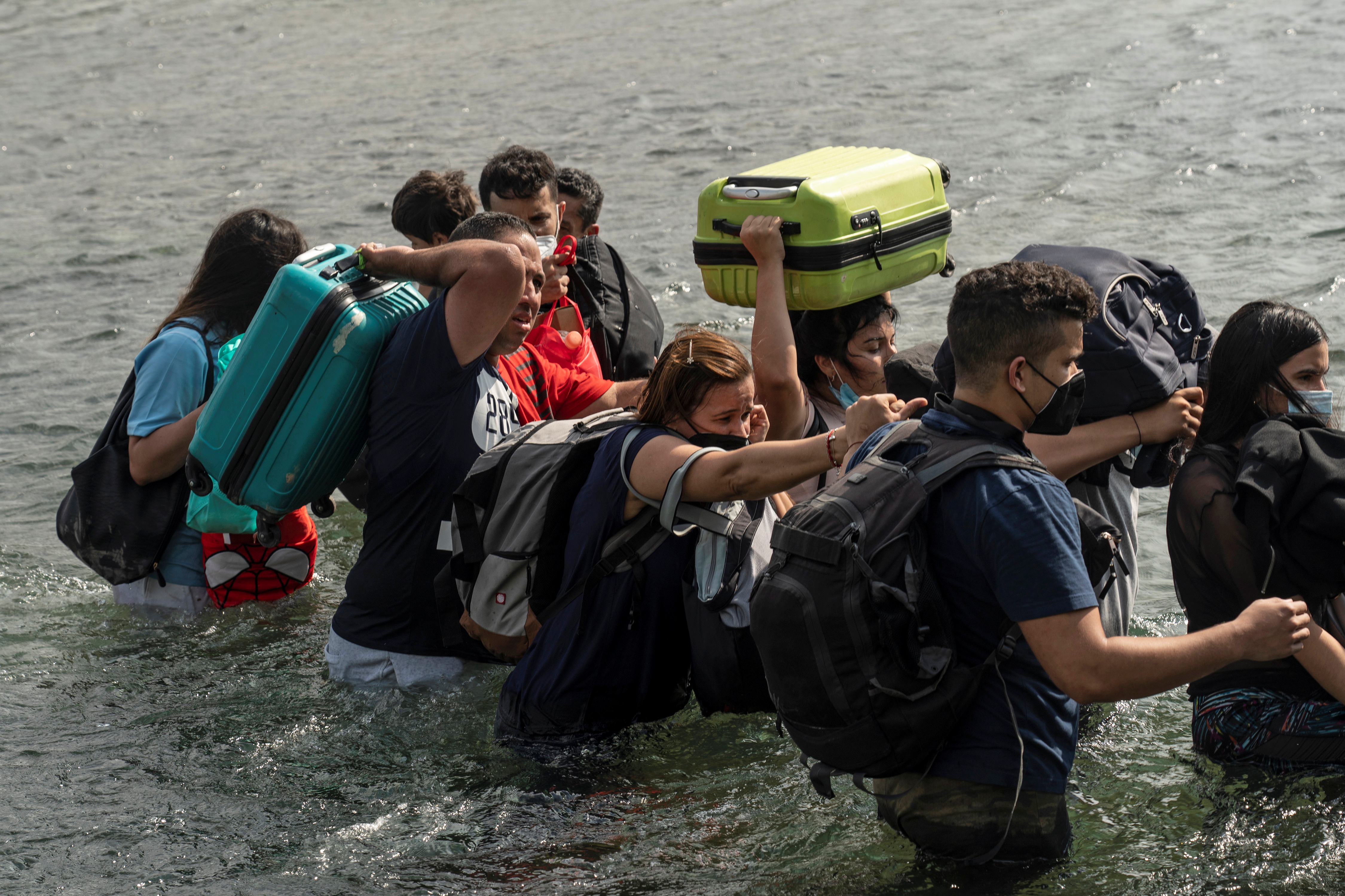 Varios venezolanos atraviesan el río con sus equipajes 