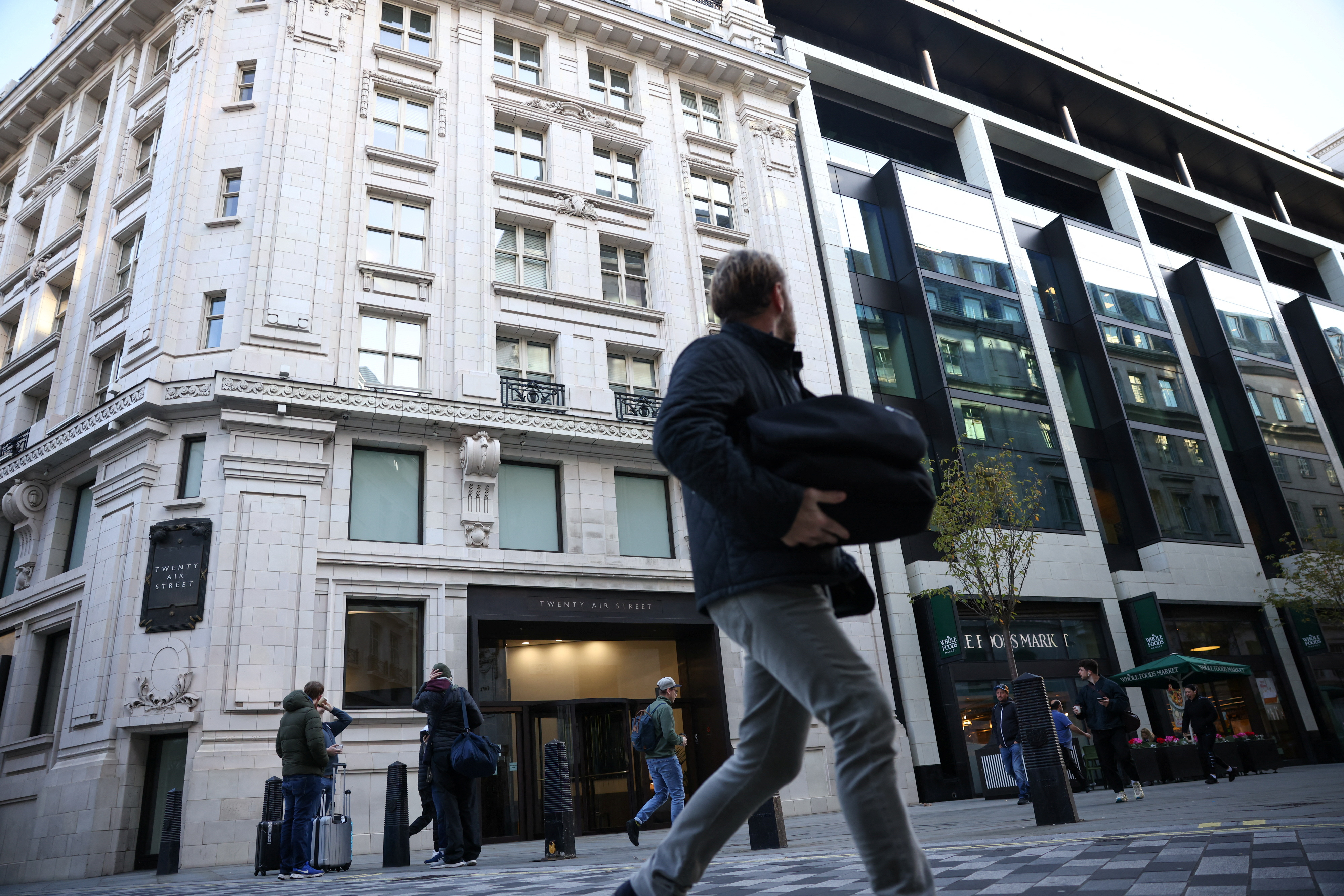 People are walking in front of the building that contains the headquarters of Twitter in the United Kingdom in the center of London, Great Britain