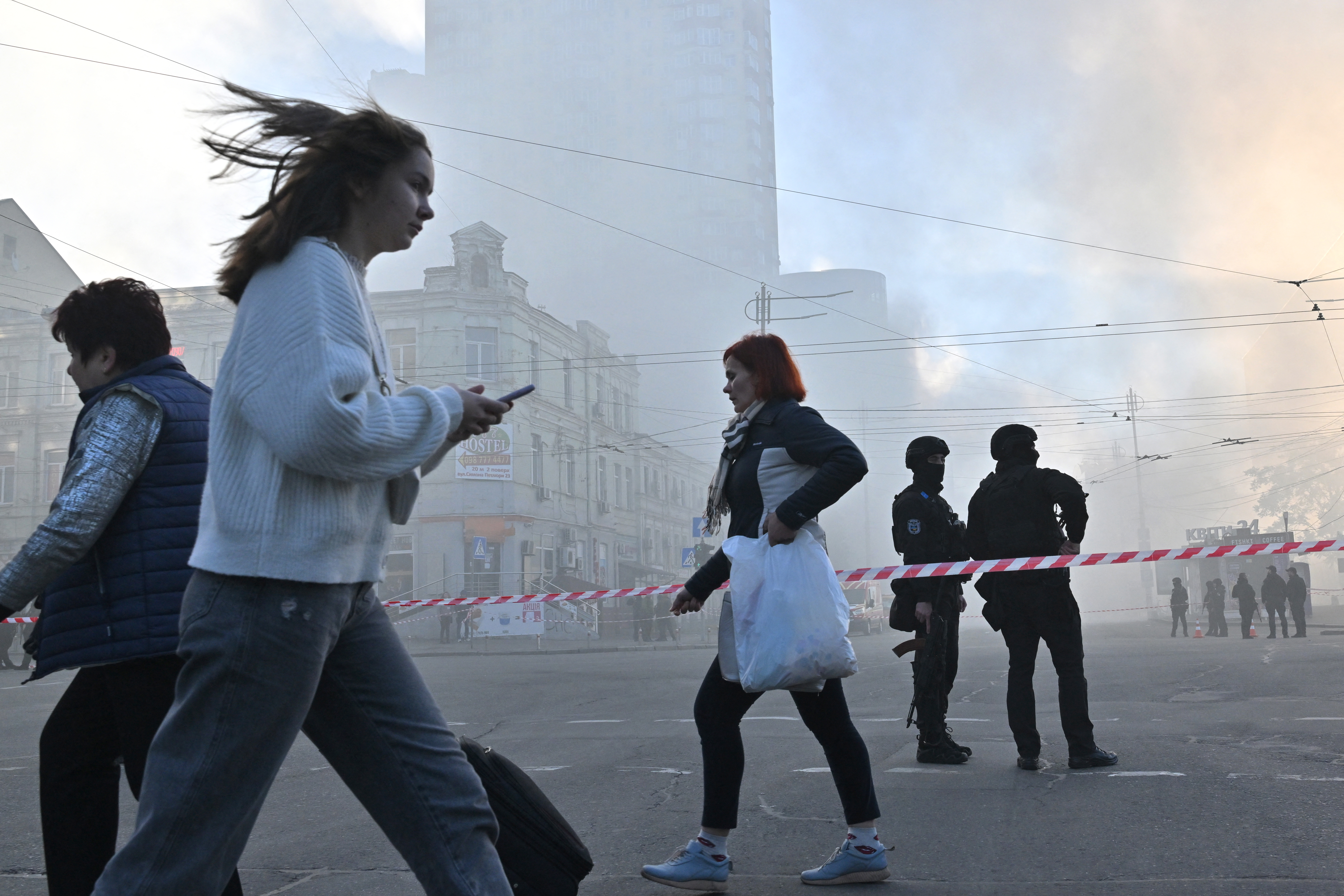 Los residentes locales pasan junto a los agentes de policía después de un ataque con drones en Kiev. (Sergei SUPINSKY / AFP)