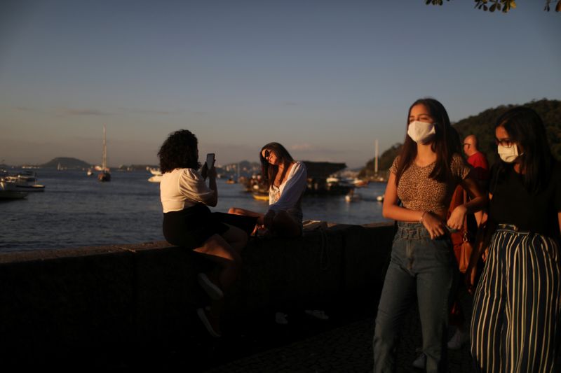 Jóvenes disfrutan del atardecer frente a un bar en el barrio carioca de Urca en medio del brote de COVID-19 en Río de Janeiro, Brasil, 8 de agosto de 2020 (REUTERS/Pilar Olivares)