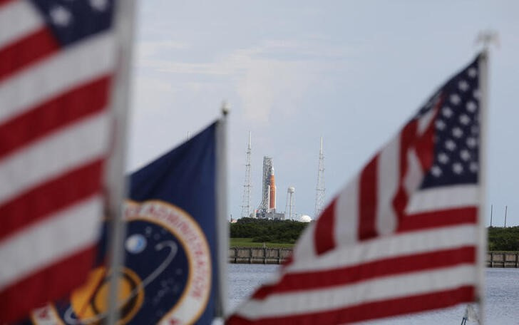 El cohete de la NASA Space Launch System (SLS) con su cápsula Orión en lo alto, visto entre banderas estadounidenses en la base de lanzamiento 39B de la misión Artemis 1 en Cabo Cañaveral (REUTERS/Thom Baur)