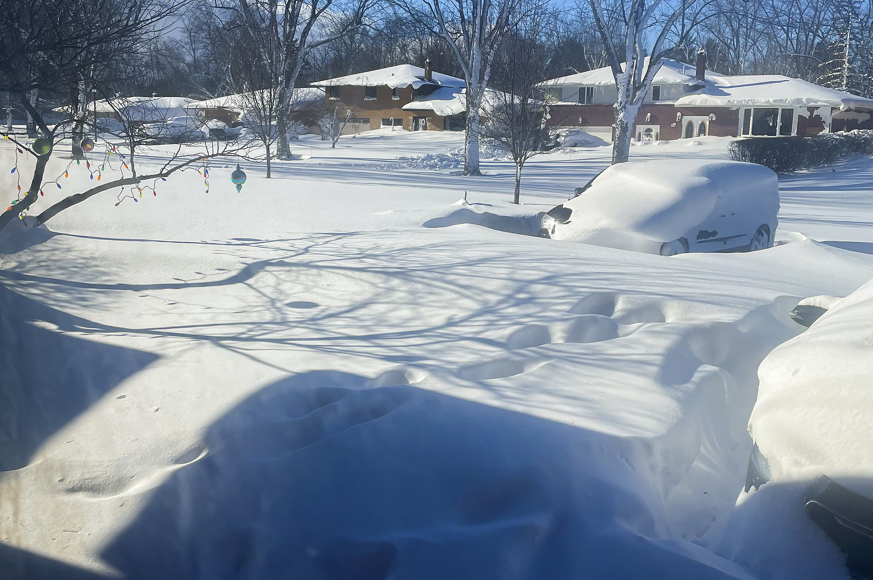 Un automóvil se encuentra cubierto de nieve en un camino de entrada, el domingo, en Amherst, Nueva York.