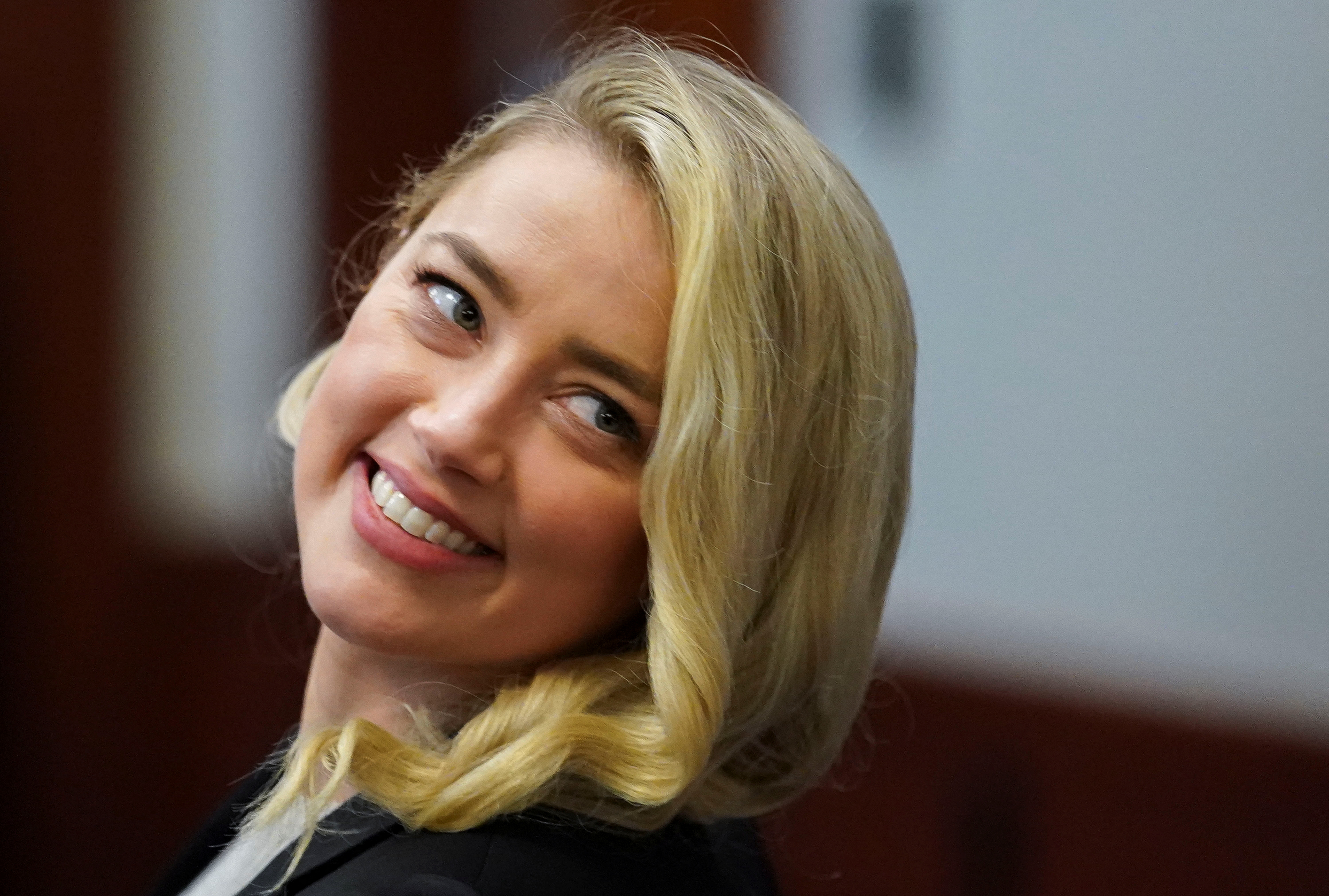 La actriz Amber Heard sonríe después de regresar de un descanso durante el juicio por difamación de su ex esposo Johnny Depp en el juzgado del circuito del condado de Fairfax en Fairfax, Virginia, EE. UU., 18 de mayo de 2022. (Foto: REUTERS/Kevin Lamarque/Pool)