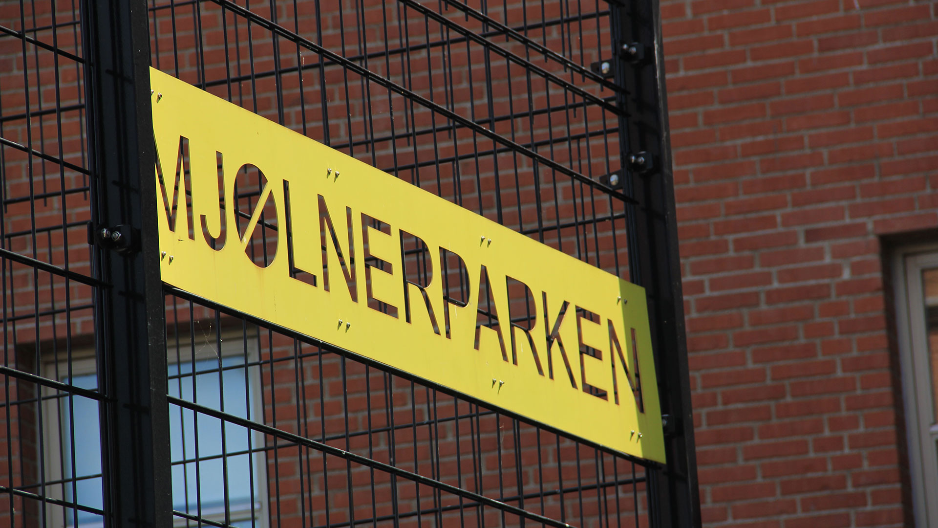 Un cartel que dice Mjølnerparken en una reja (Creative commons)
