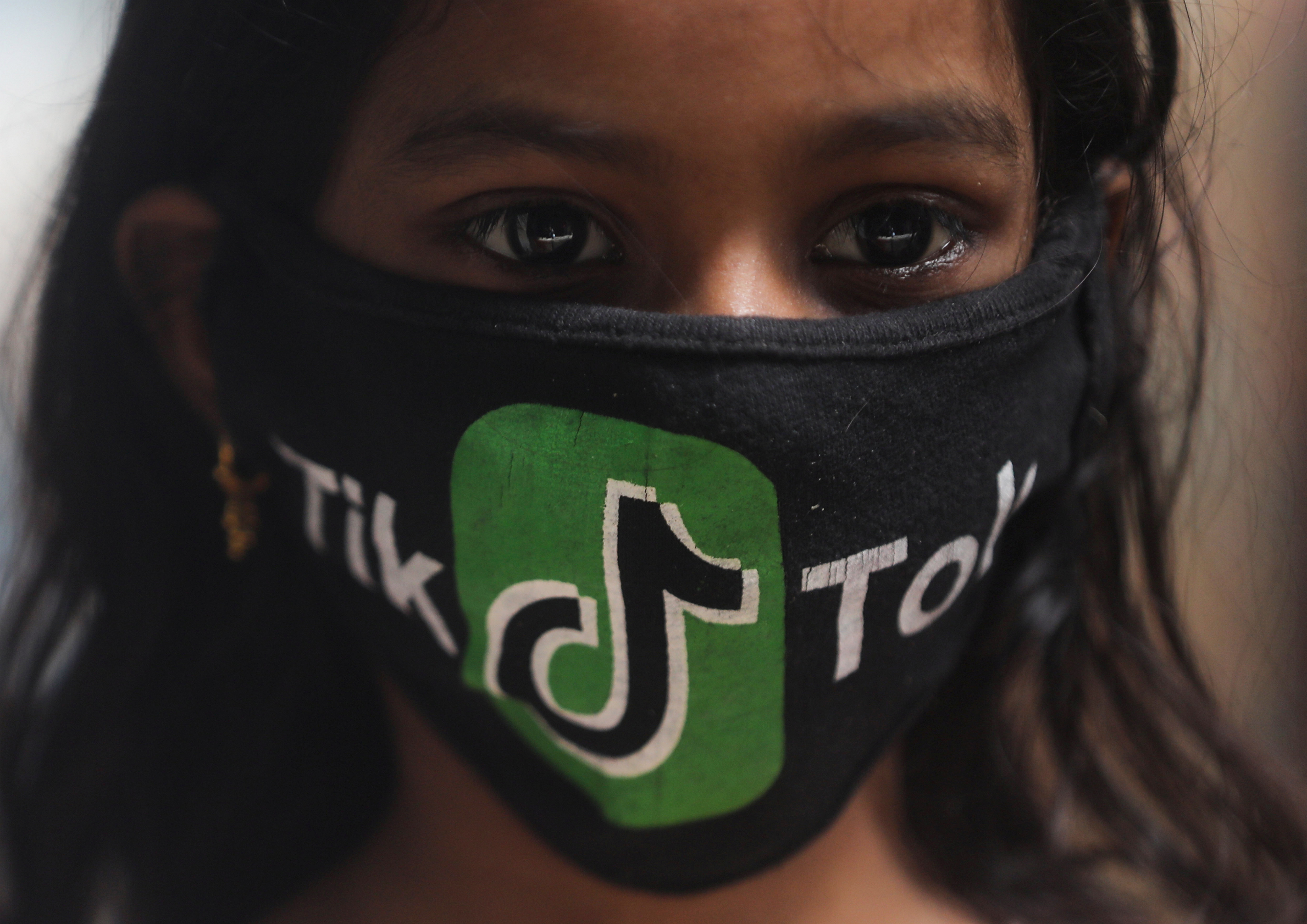 Una joven usa una mascarilla con el logo de TikTok en una barriada de Mumbai (Reuters)