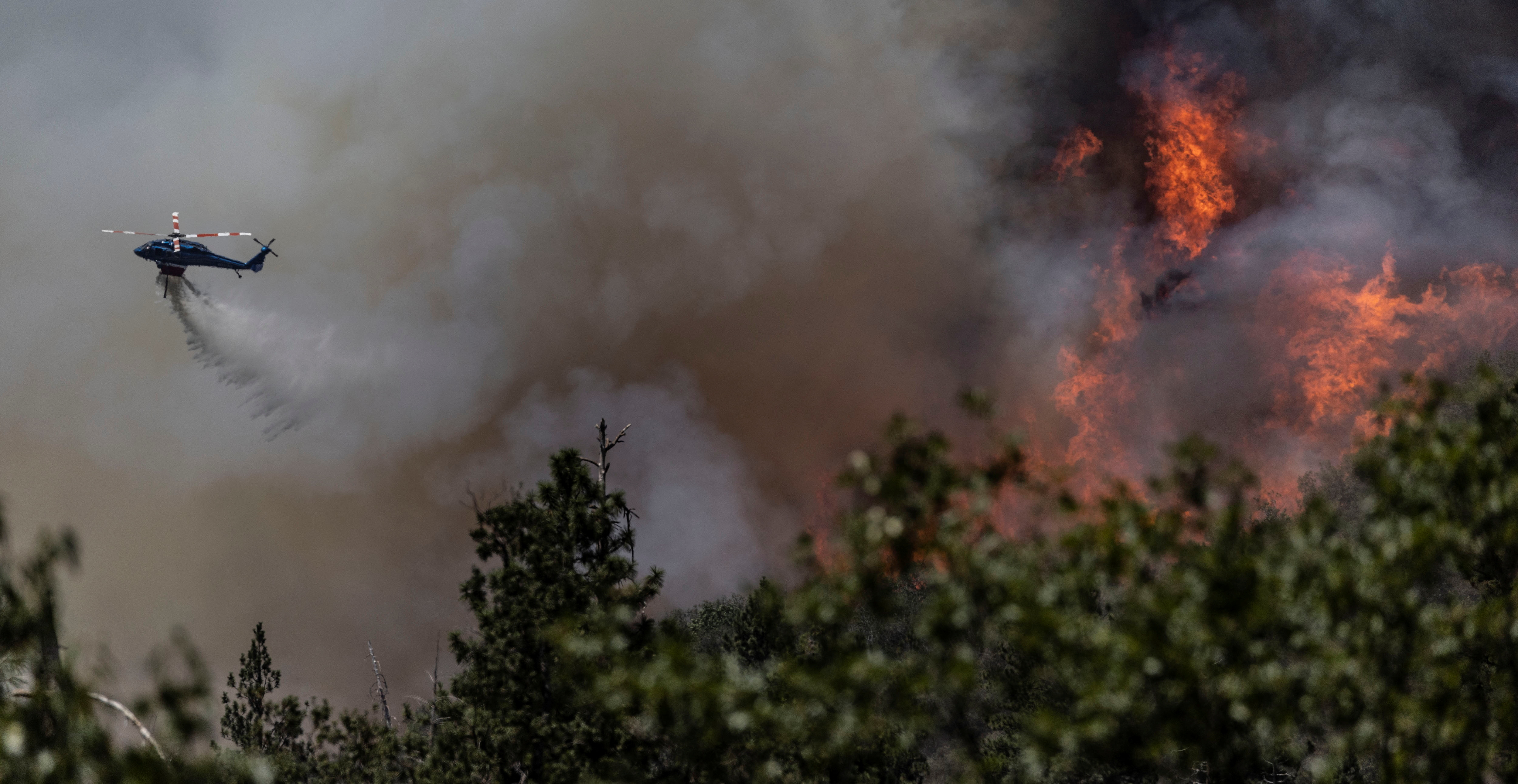 Un helicóptero de extinción de incendios arroja agua en la ladera de una colina para controlar el Oak Fire mientras arde cerca de Darrah en el condado de Mariposa, California, EE. UU., el 24 de julio de 2022. REUTERS/Carlos Barria