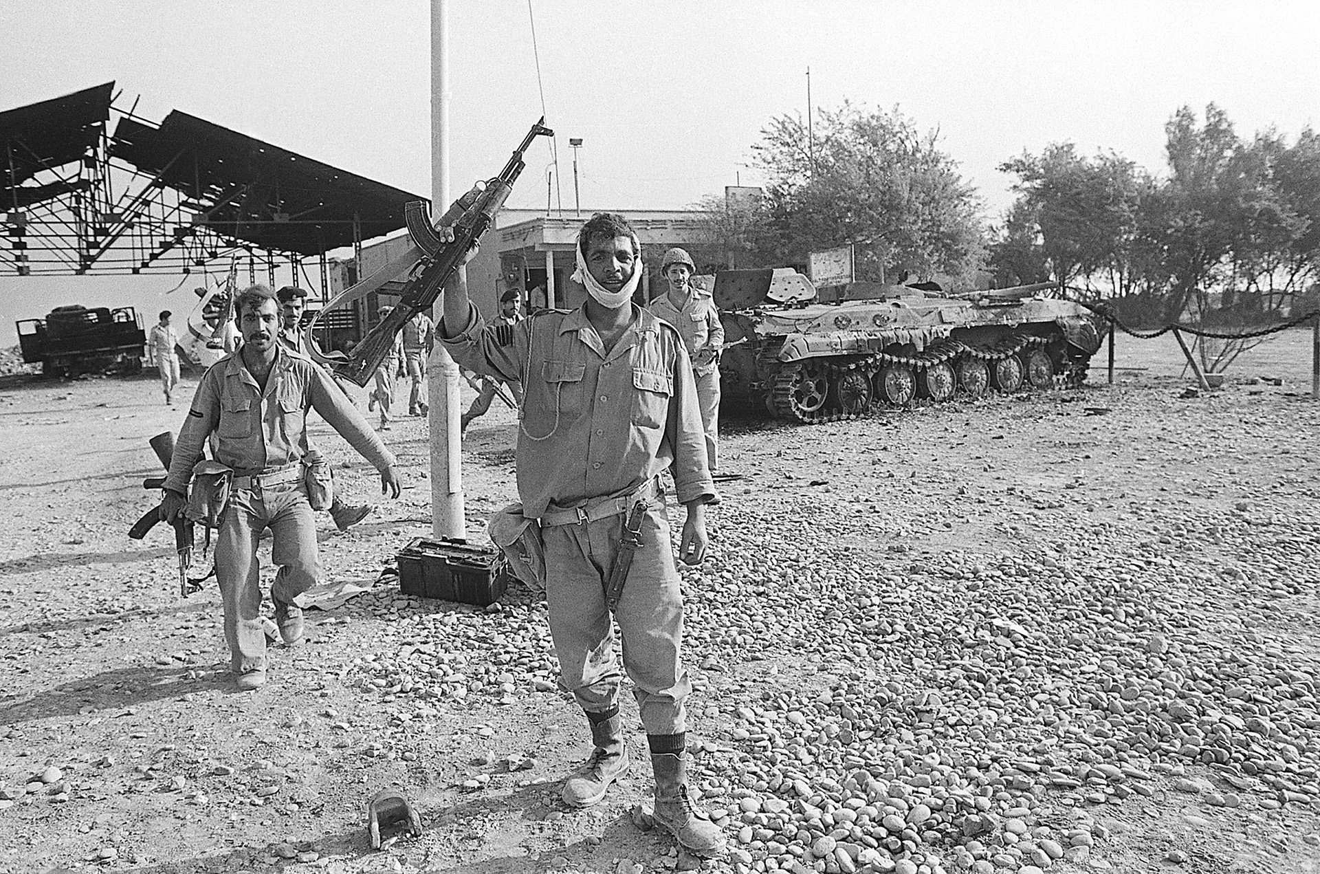 Irán ocupado por Iraken 1980. Un soldado porta armas automáticas AK-47, mientras pasan junto a un tanque iraní destruido (Getty Images)