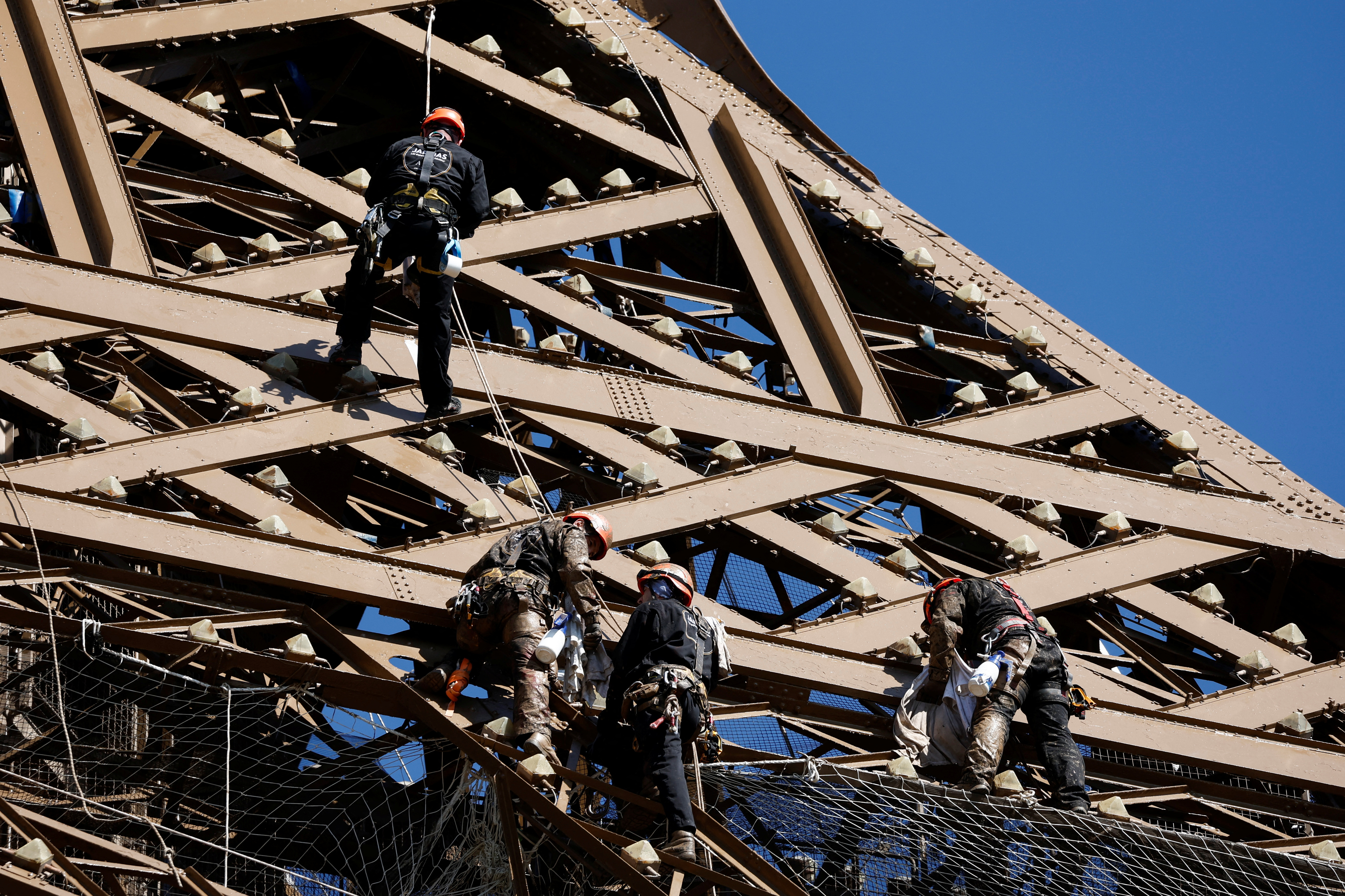 Workers work on the Eiffel tower during the 20th campaign of painting and stripping in Paris, France, July 5, 2022. REUTERS/Benoit Tessier