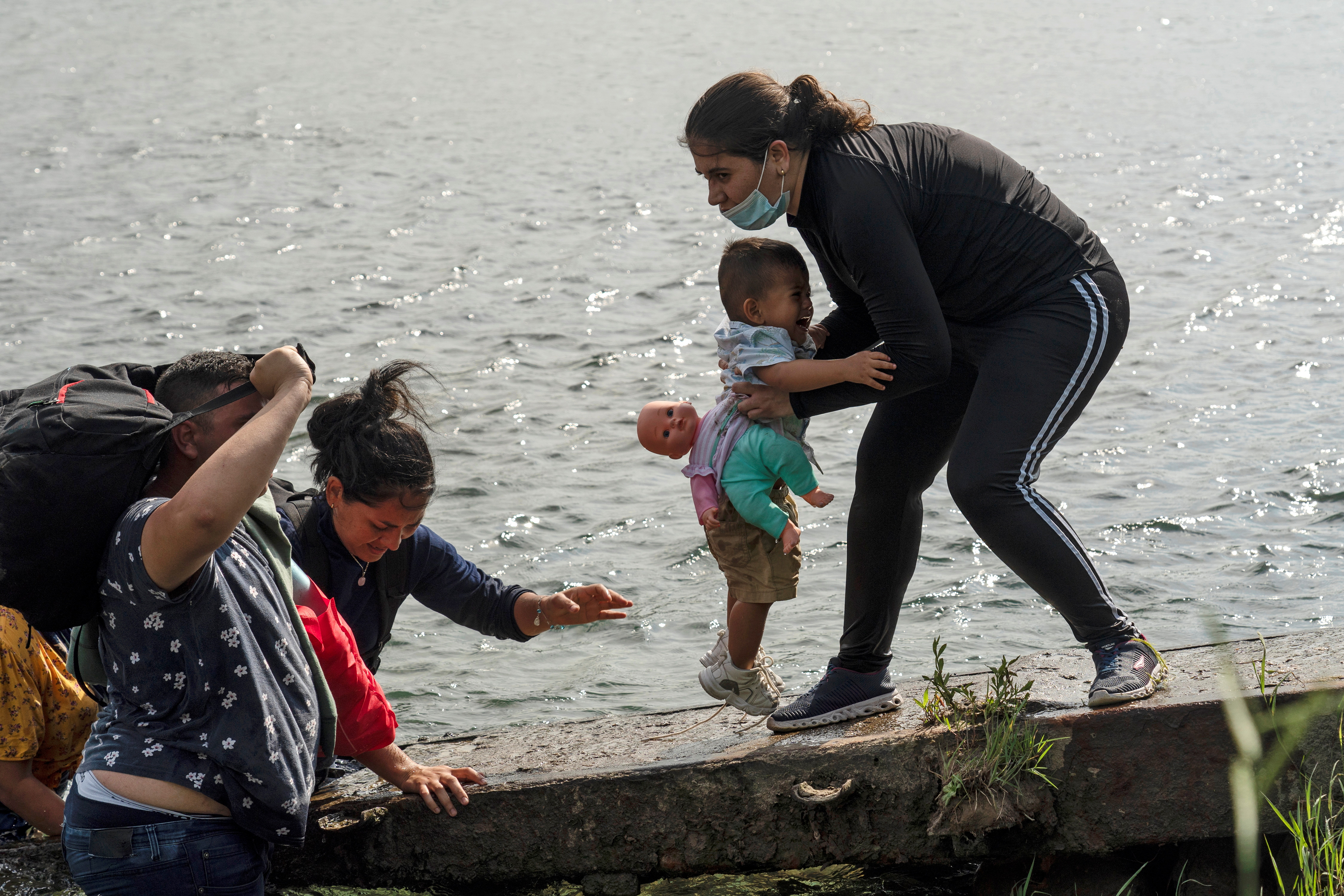 Una mujer venezolana carga un bebé en el río Grande 