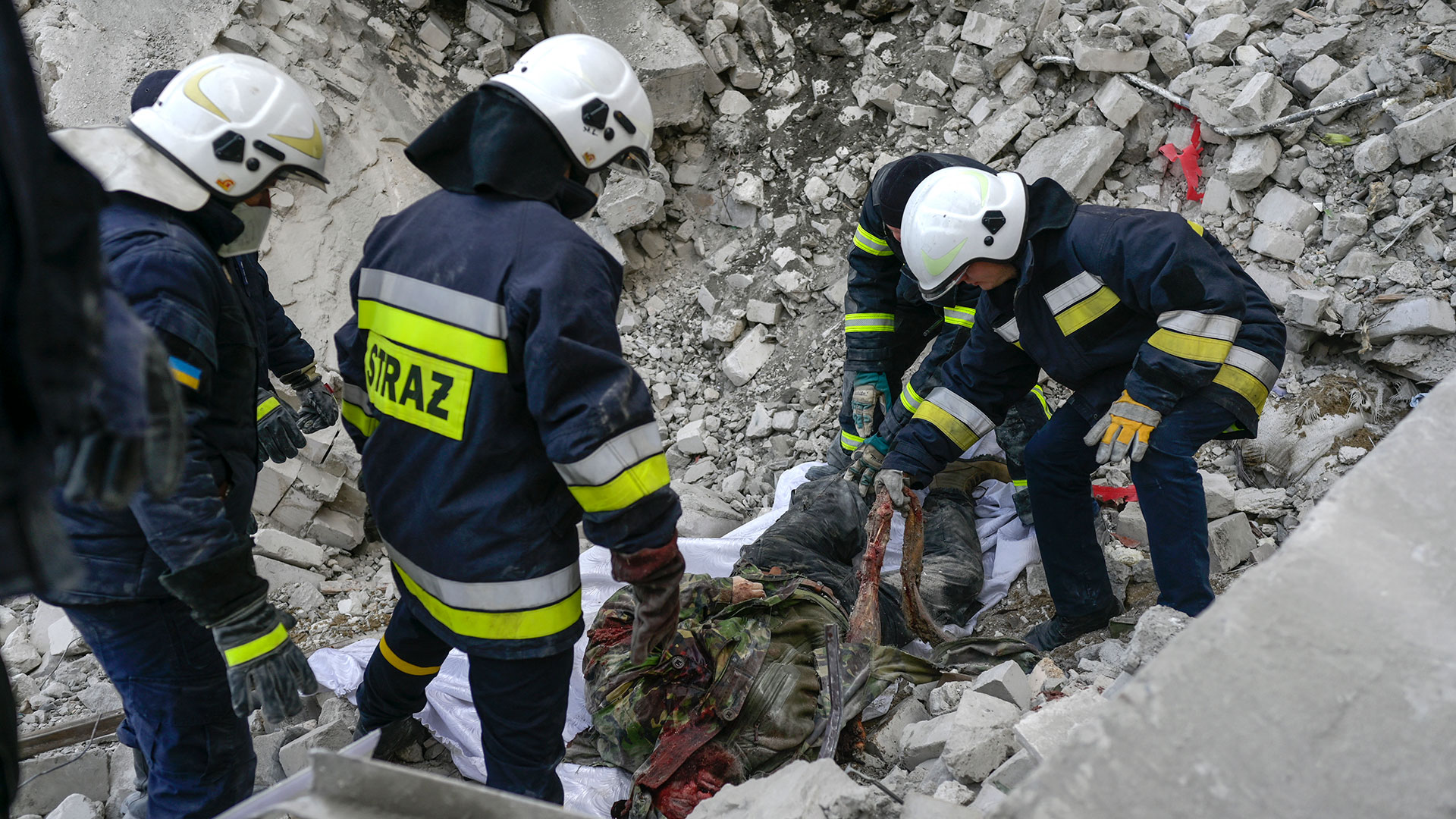 Los bomberos sacan un cadáver de los escombros de un edificio del gobierno alcanzado por cohetes rusos en Mykolaiv (AFP)