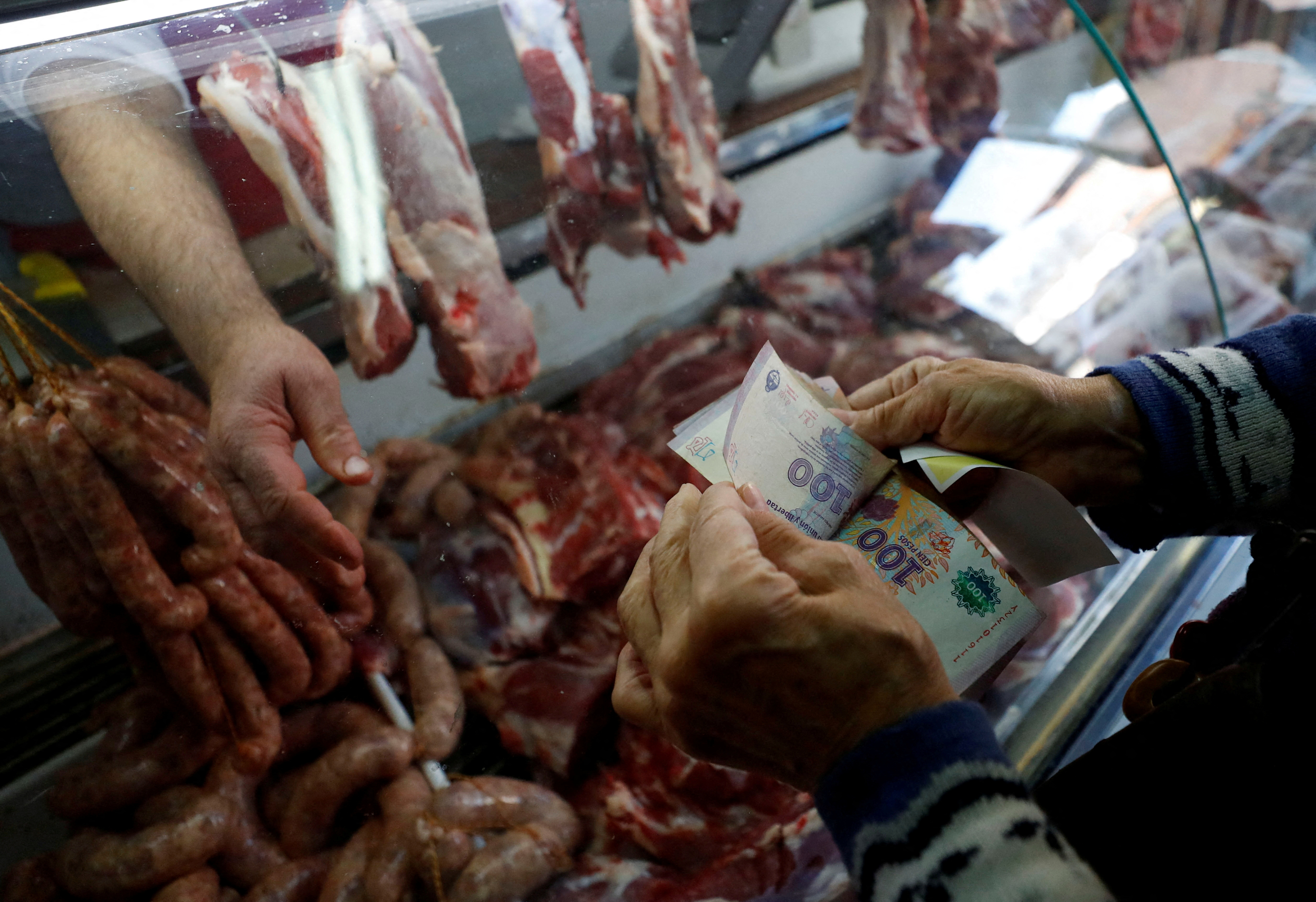 FILE PHOTO: A customer counts money  before paying at a butcher shop, as inflation in Argentina hits its highest level in years, causing food prices to spiral, in Buenos Aires, Argentina September 13, 2022. REUTERS/Agustin Marcarian/File Photo