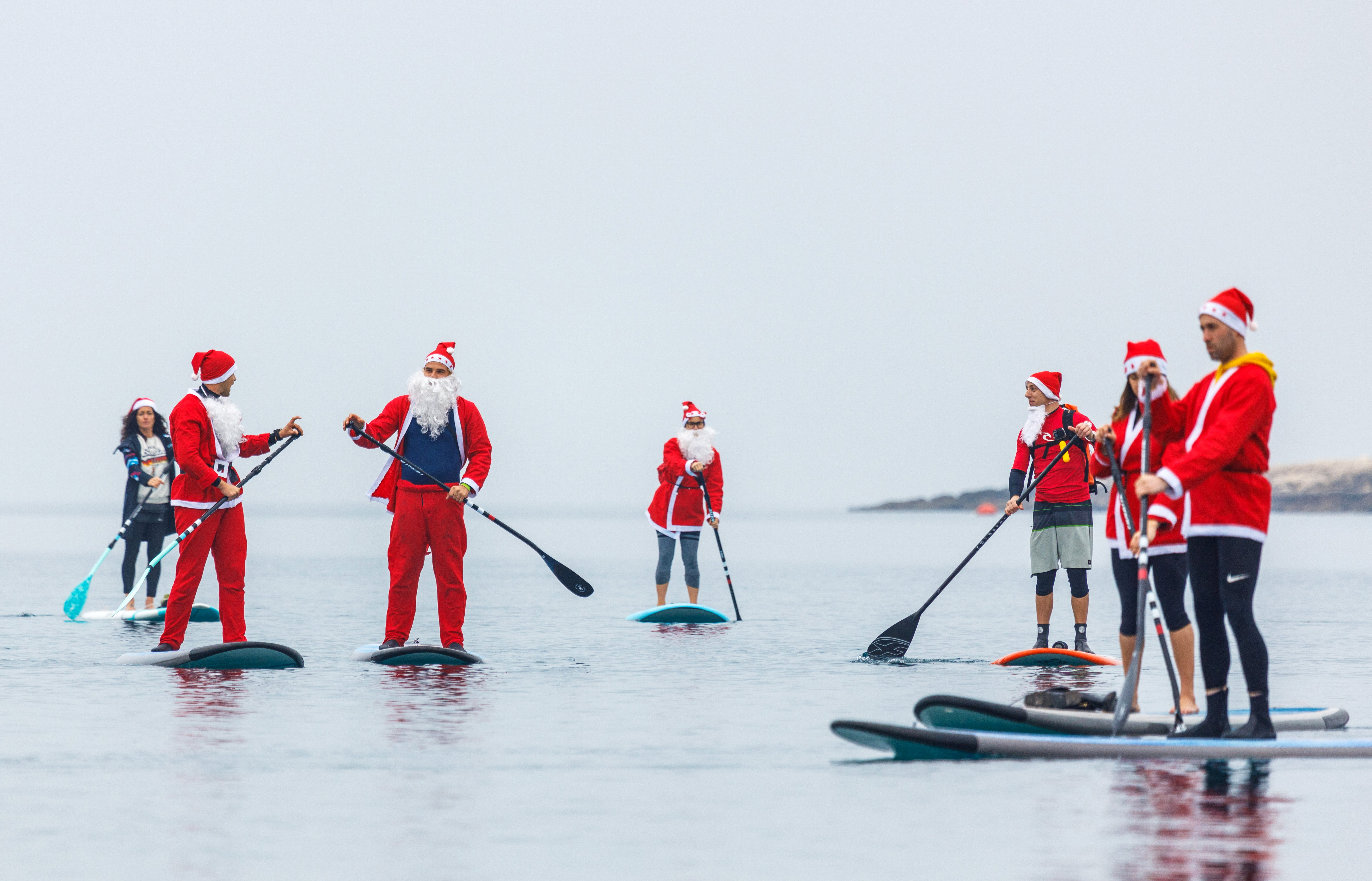 Gente vestida de Papá Noel rema en tablas de SUP en Pula, Croacia (REUTERS/Antonio Bronic)