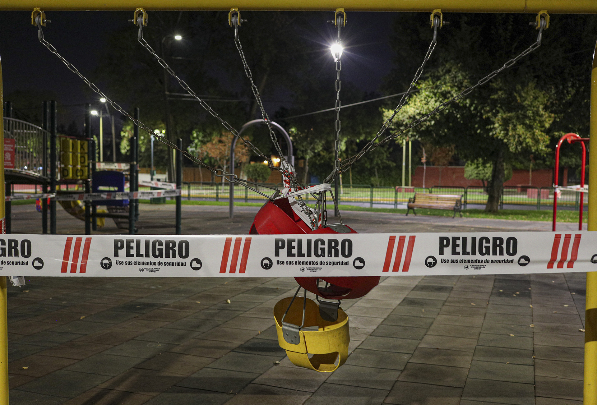 Los columpios de un parque infantil, atados entre sí y precintados con una cinta con la palabra