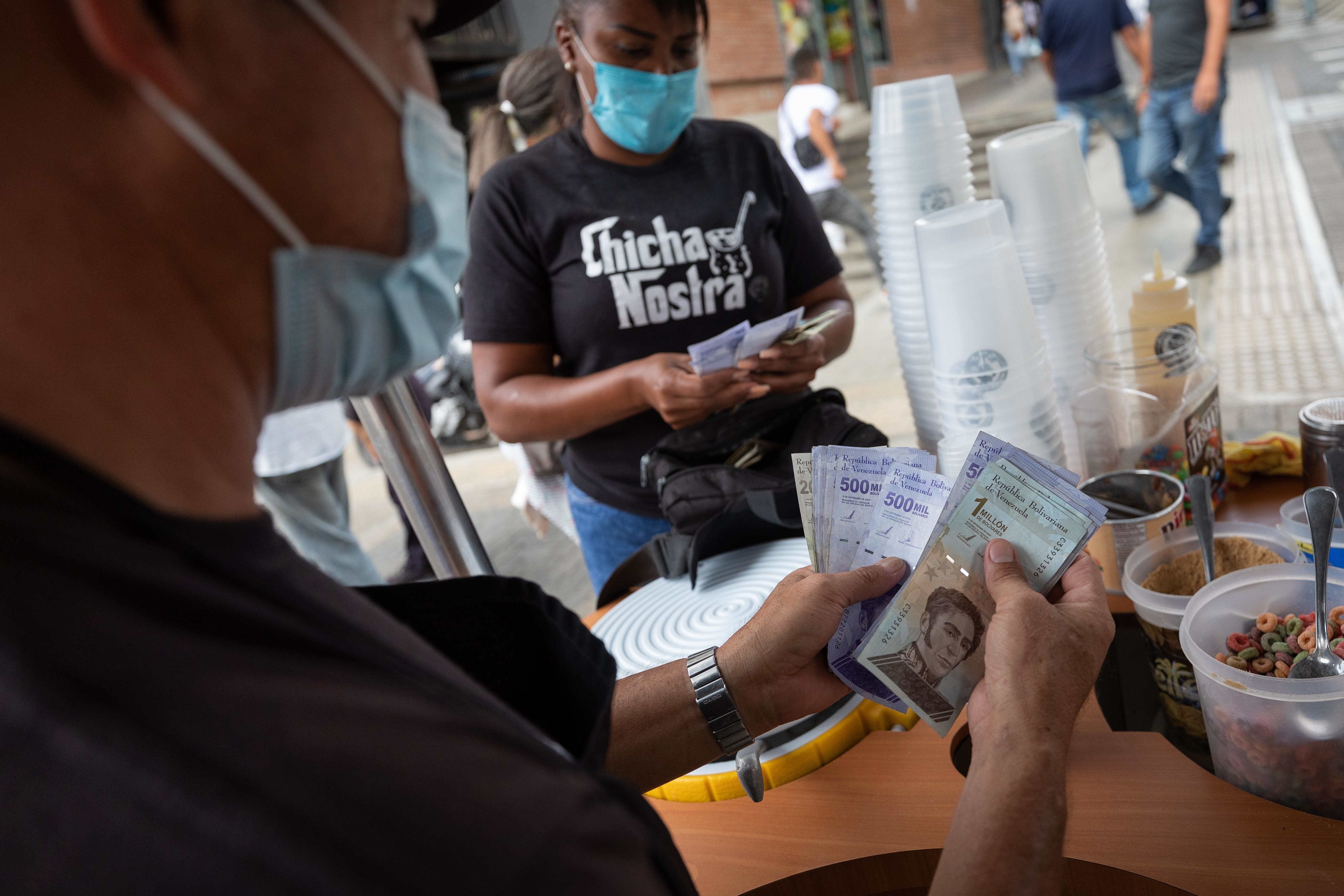 Vendedores cuentan billetes del antiguo cono monetario (Bolívar Soberano), el 22 de octubre de 2021, en Caracas (Venezuela). EFE/ Rayner Peña R
