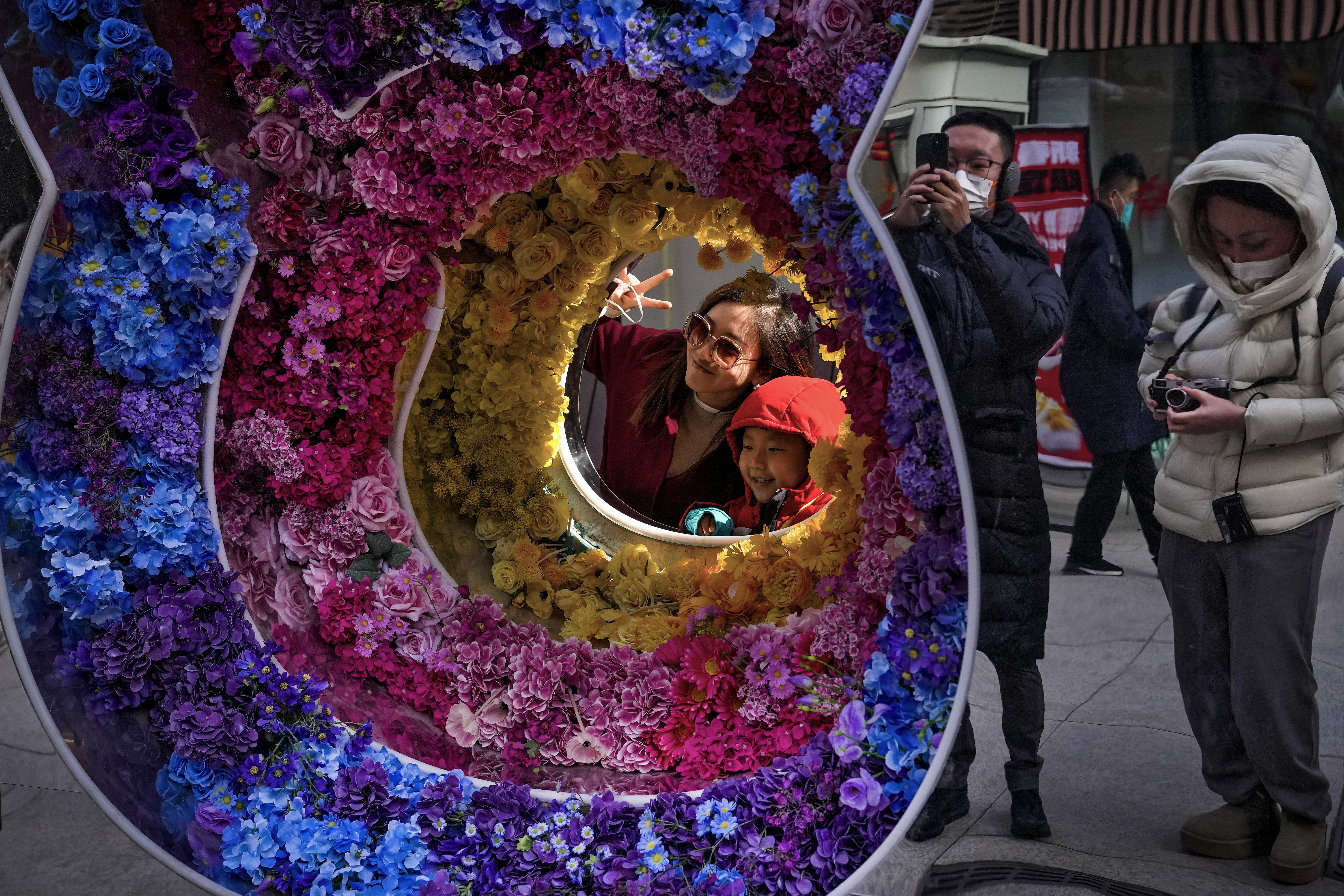 A woman and a girl pose for a souvenir photo with rabbit-shaped floral decorations at a pedestrian street in Qianmen, on the first day of the Year of the Rabbit in Beijing, Sunday, Jan. 22, 2023. People across China celebrated the change of the lunar year on Sunday with large family gatherings and massive visits to temples, after the government withdrew its strict measures of "zero COVID", in the first full-scale celebration since the pandemic began three years earlier.  (AP Photo/Andy Wong)