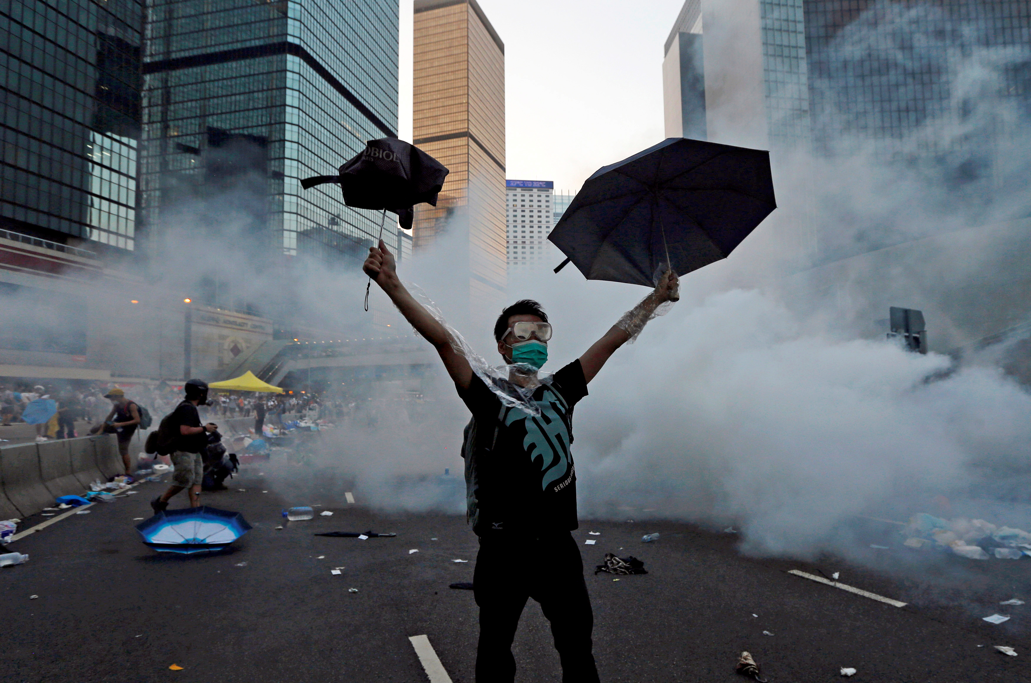 Un manifestante levanta sus paraguas frente al gas lacrimógeno que fue disparado por la policía antidisturbios para dispersar a los manifestantes que bloquean la calle principal hacia el distrito financiero central fuera de la sede del gobierno en Hong Kong, China, el 28 de septiembre de 2014. Foto tomada el 28 de septiembre de 2014. REUTERS