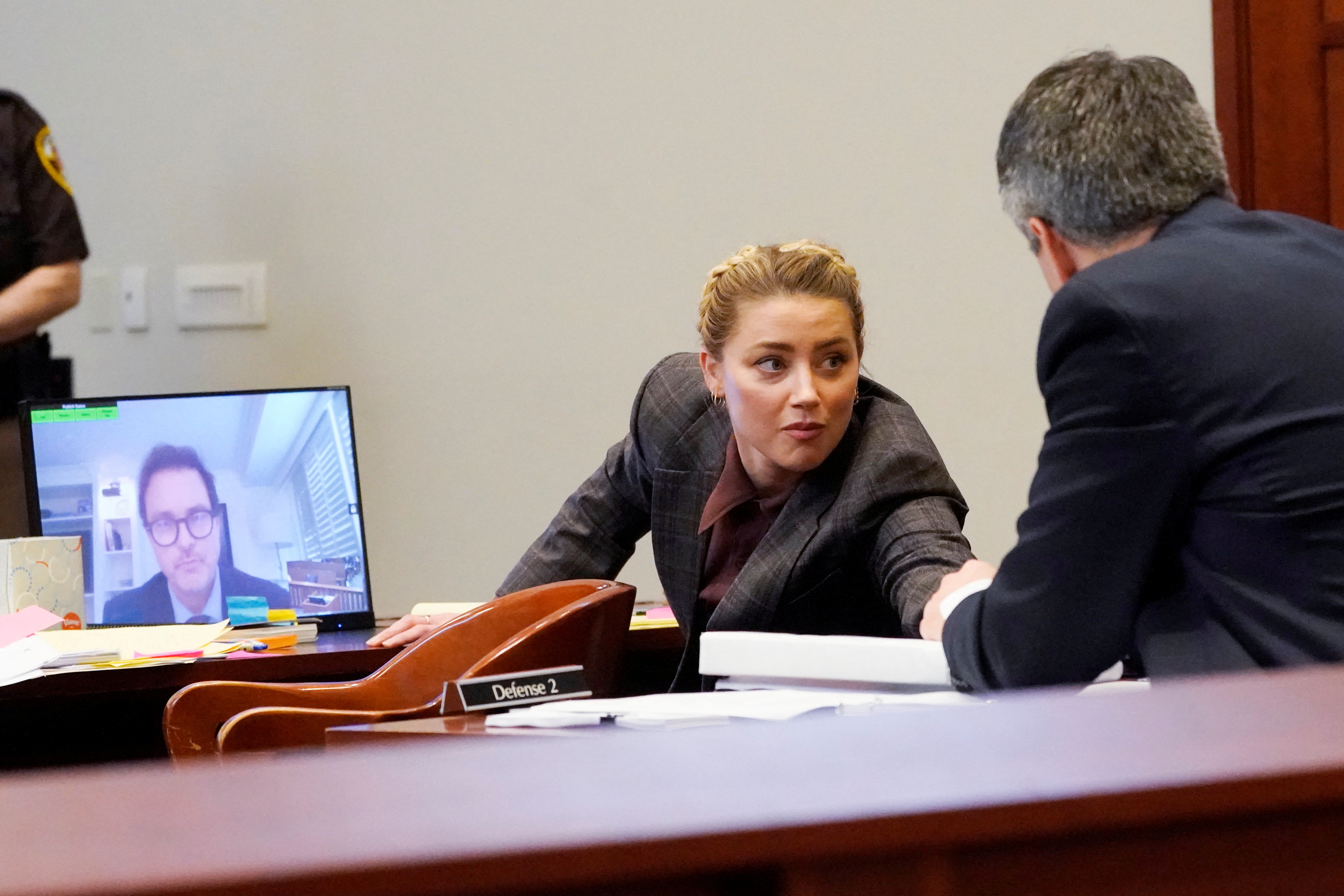 Actor Amber Heard talks to her attorney as Jack Whigham, talent manager for Johnny Depp, is seen on a monitor as he testifies remotely at Fairfax County Circuit Court during a defamation case against her by Depp, her ex-husband, in Fairfax, Virginia, U.S., May 2, 2022. Steve Helber/Pool via REUTERS