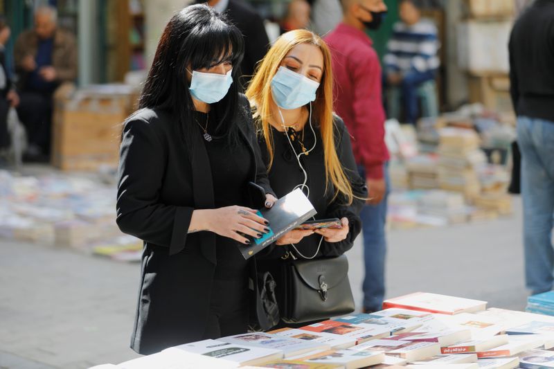 Mujeres iraquíes usan mascarillas mientras miran libros en Bagdad (REUTERS/Khalid al-Mousily)