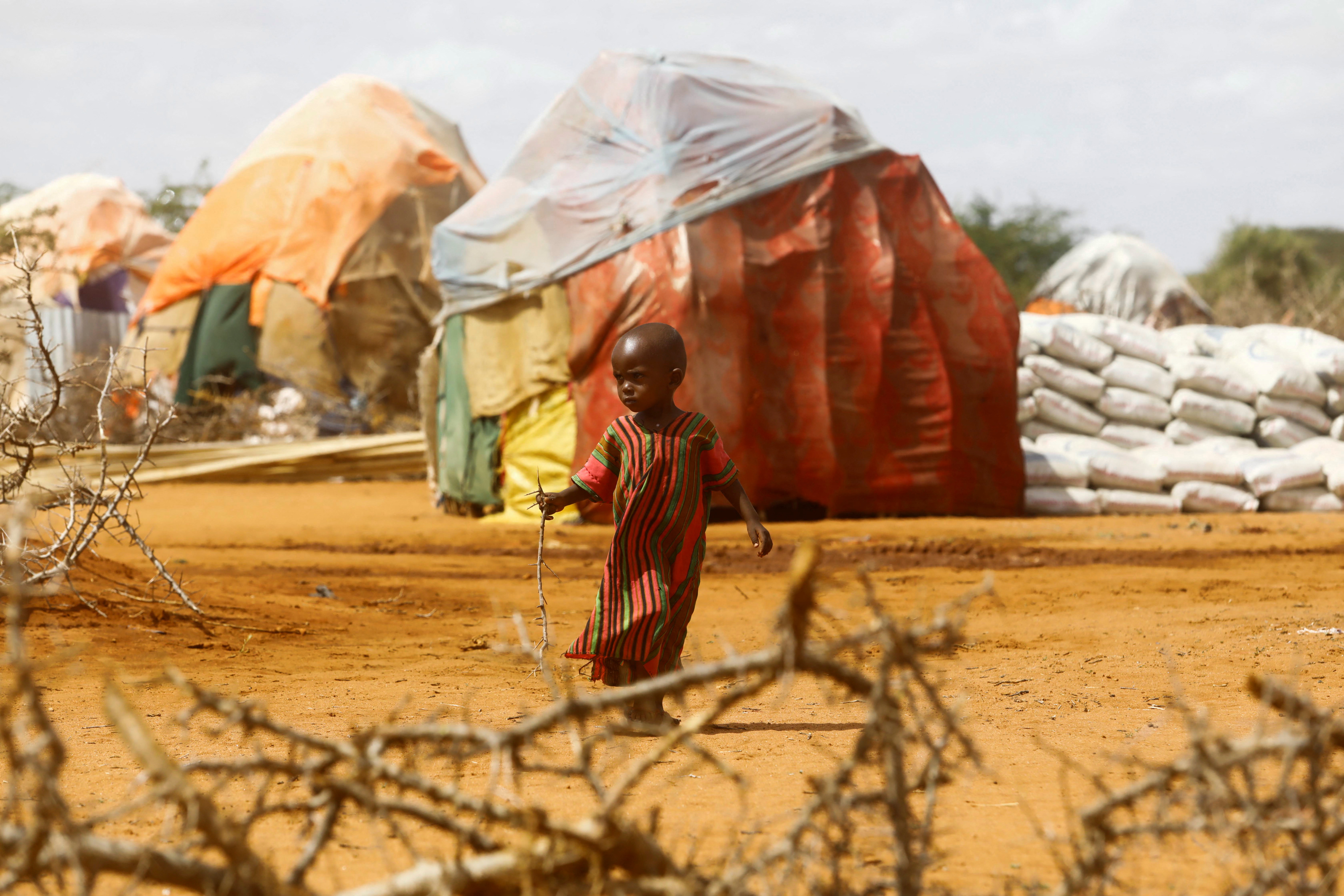 Un niño camina fuera de los refugios improvisados en el campamento de Kaxareey para los desplazados internos después de que huyeron de las graves sequías, en Dollow, región de Gedo, Somalia (Reuters)