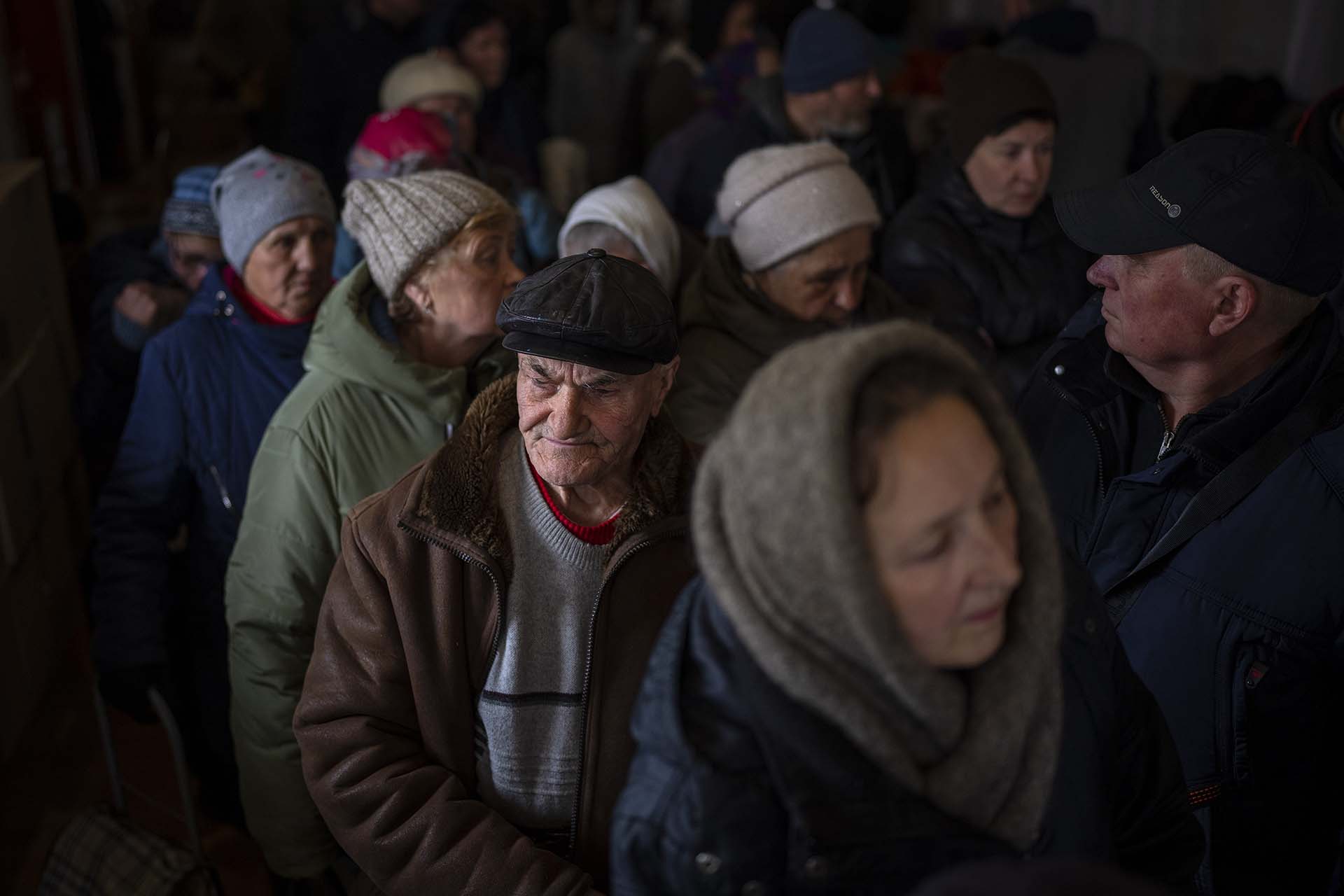 Hombres ucranianos hacen cola dentro de una iglesia para recibir ayuda humanitaria donada por la Unión Europea en Bucha, en las afueras de Kiev, el martes 19 de abril de 2022. Los ciudadanos de Bucha siguen sin electricidad, agua y gas después de más de 44 días desde que los rusos comenzó la invasión (AP Photo/Emilio Morenatti)