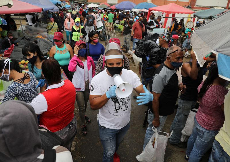 Walter Rivera, director del mercado mayorista Coche, anuncia con un megáfono las reglas para evitar el coronavirus a locatarios y clientes en Caracas, Venezuela (REUTERS/Manaure Quintero)