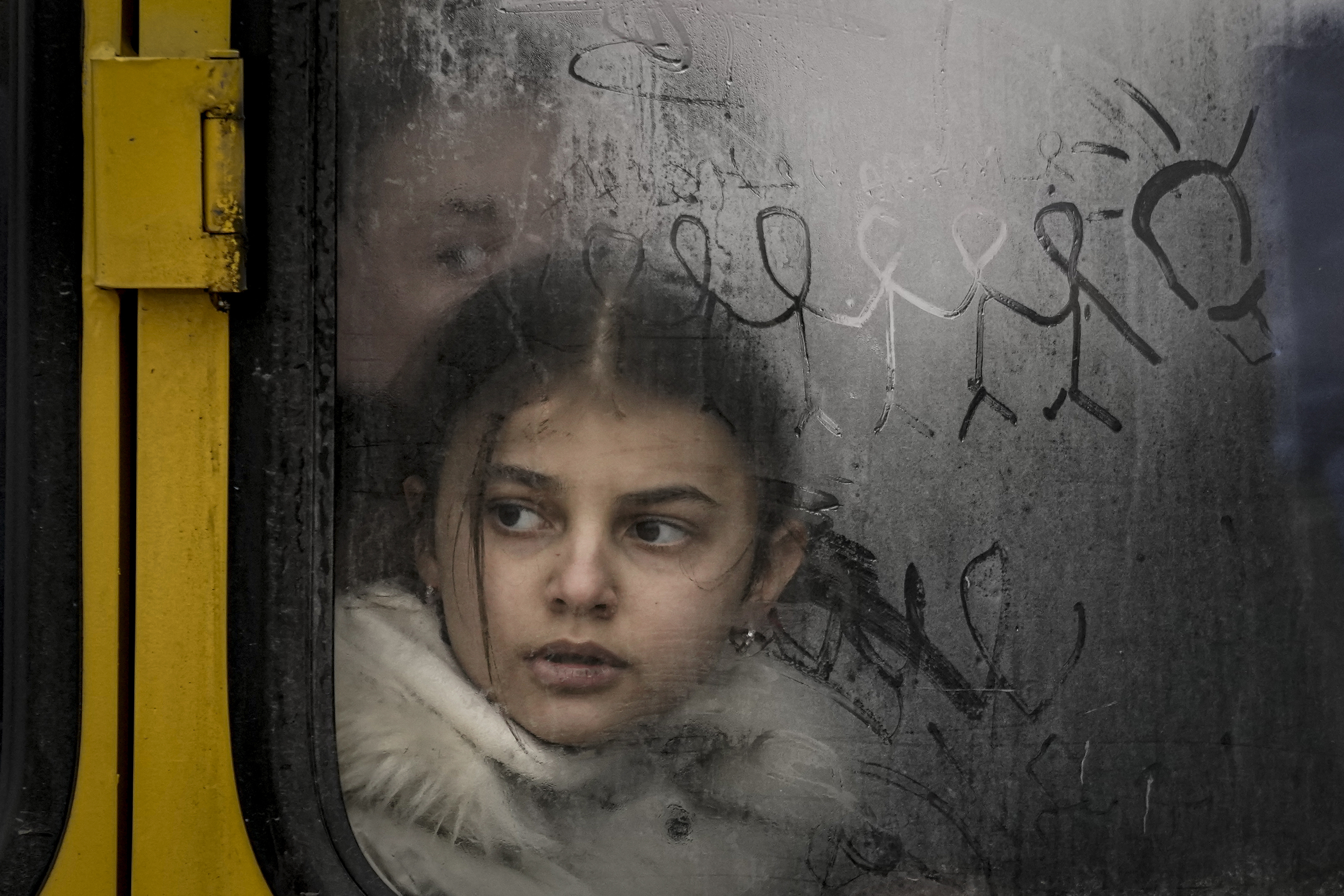 Una niña mira por la ventana de un autobús con dibujos mientras los civiles son evacuados de Irpin, en las afueras de Kiev, Ucrania (AP)