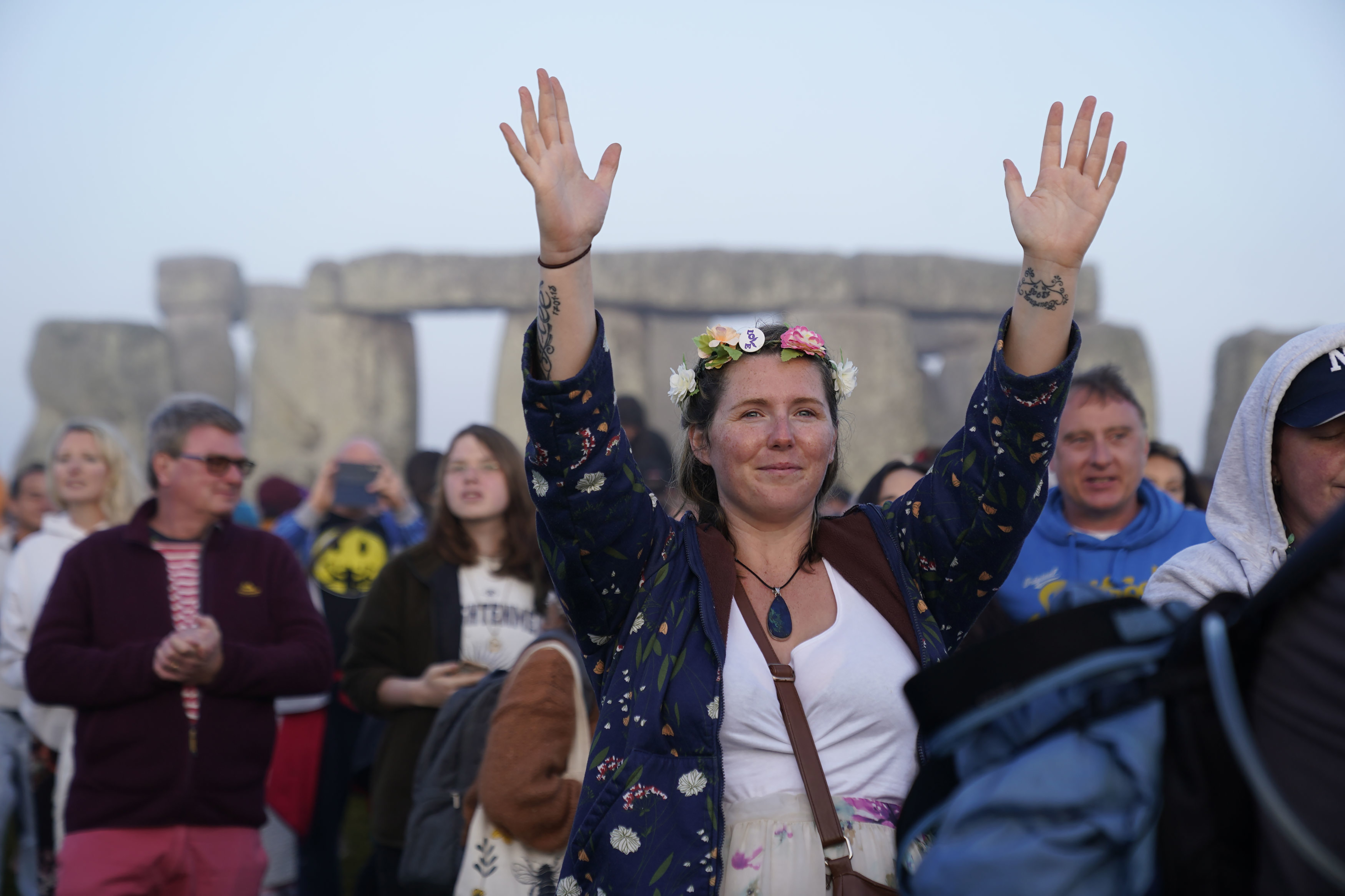 Gente reunida al amanecer en las celebraciones del Solsticio de Verano levantan las manos para recibir la energía del sol.