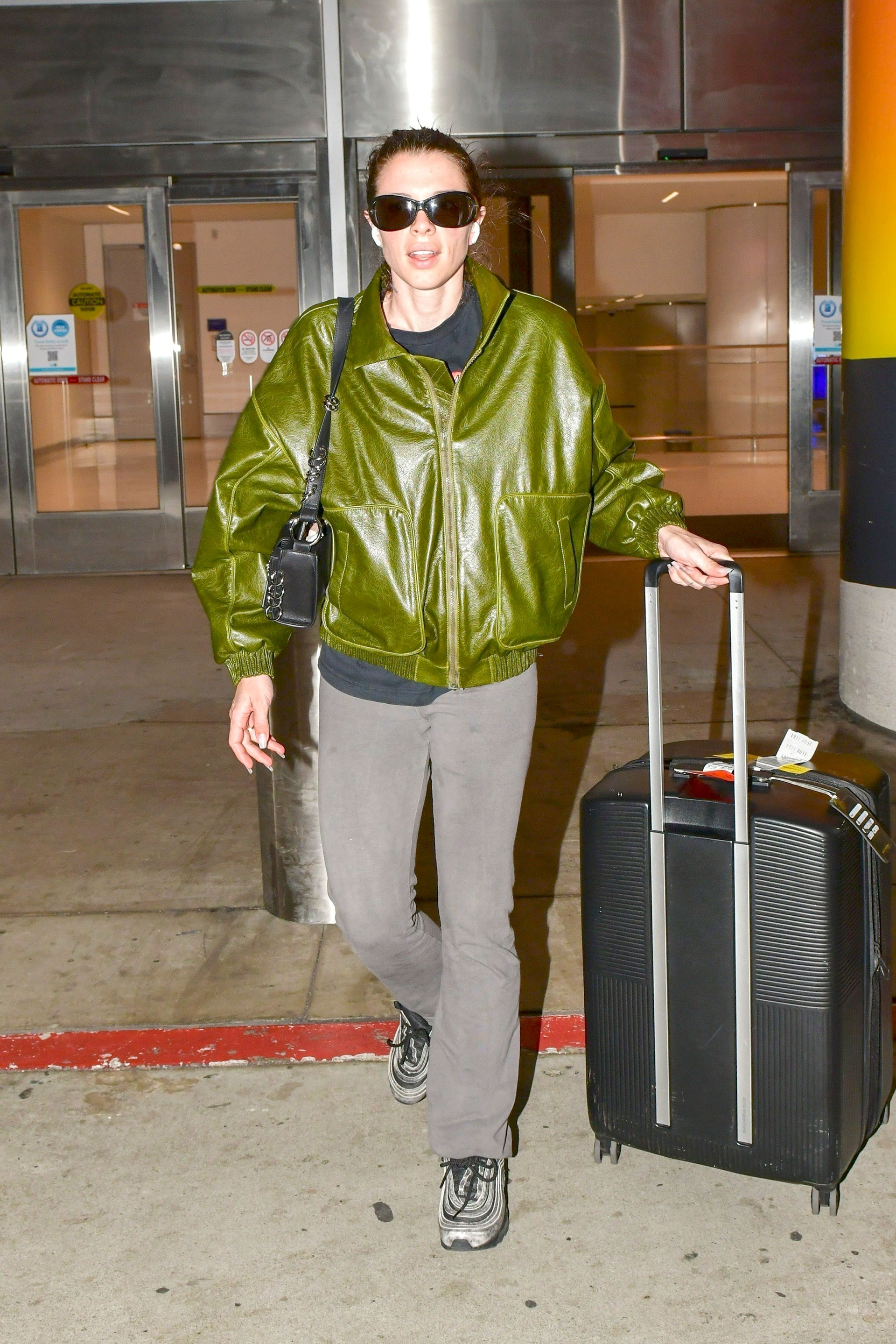 Julia Fox fue fotografiada en el aeropuerto de Los Ángeles, a donde regresó de un viaje de trabajo, y marcó tendencia con su look: una campera verde de cuero, pantalón gris que combinó con sus zapatillas, y cartera de cuero. Además, llevó lentes de sol