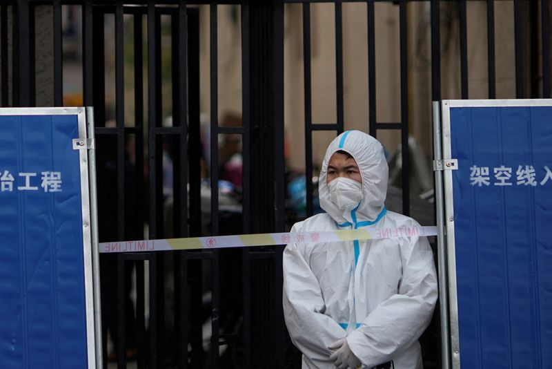 Un trabajador sanitario con un equipo de protección individual tras la barrera de un área confinada por causa de la pandemia de COVID-19 en Shanghái, China. REUTERS/Aly Song